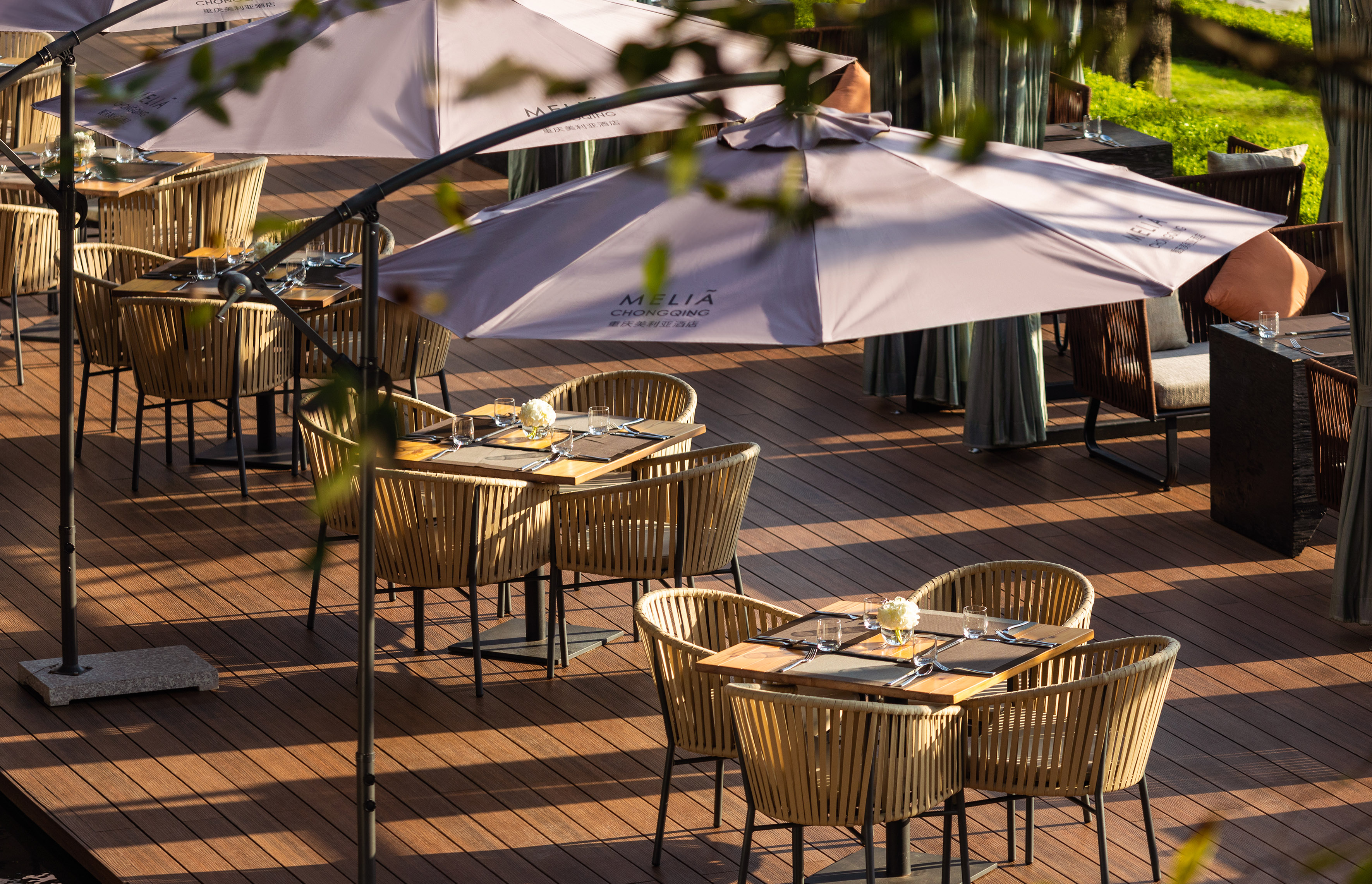 Meliá Chongqing hotel outdoor patio with dining tables, wicker chairs, and umbrellas.