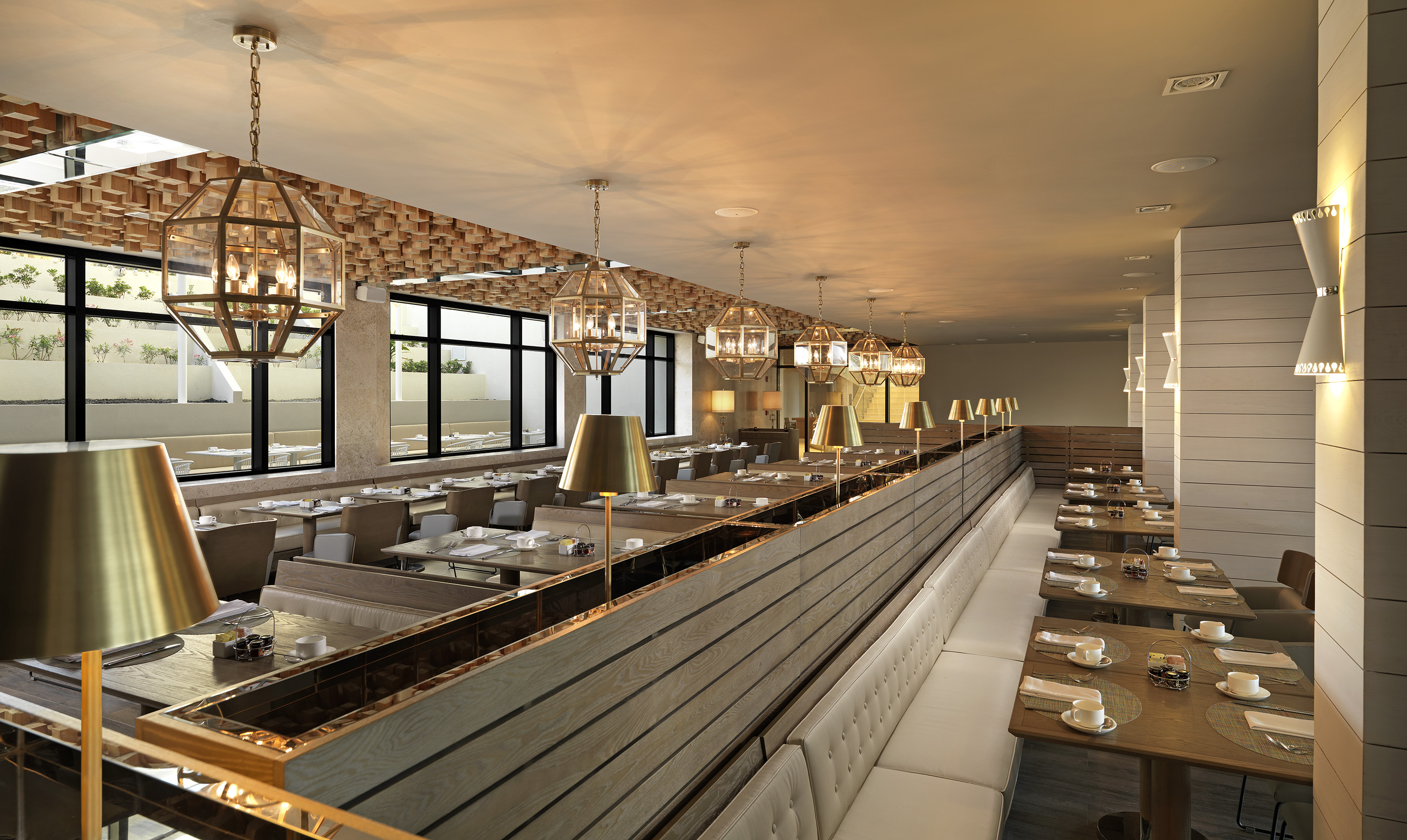 Modern dining room with geometric chandeliers, booth seating, and set tables.