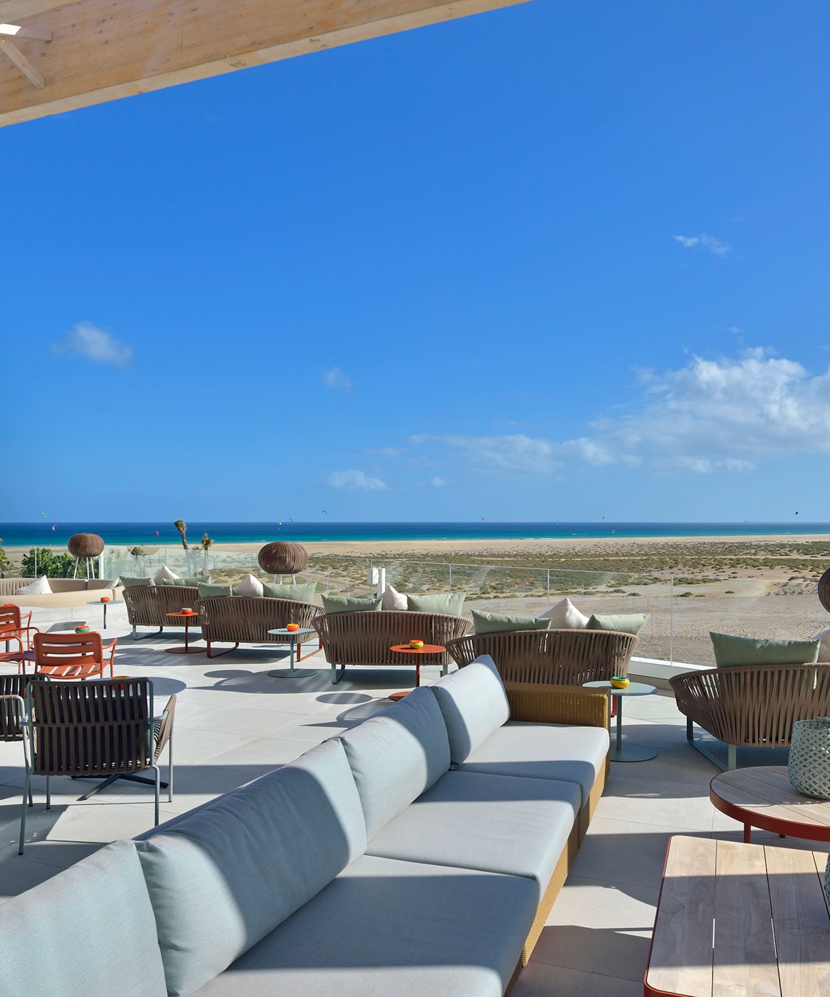 a patio with furniture and chairs on the beach