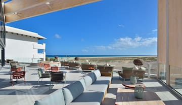 a patio with furniture and chairs on the beach