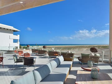 a patio with furniture and chairs on the beach