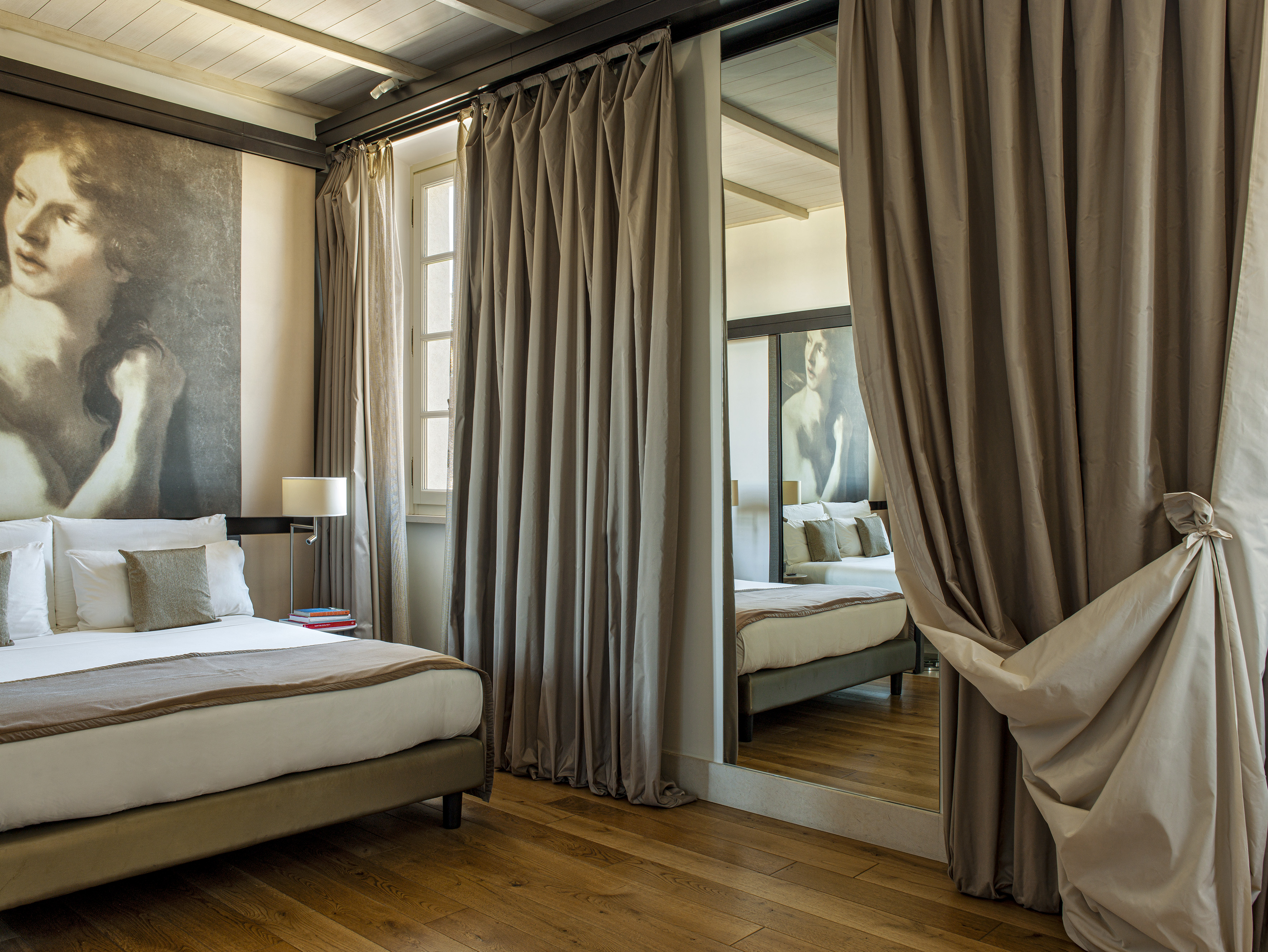 Elegant hotel bedroom with large artistic mural, bed, and mirrored partition.