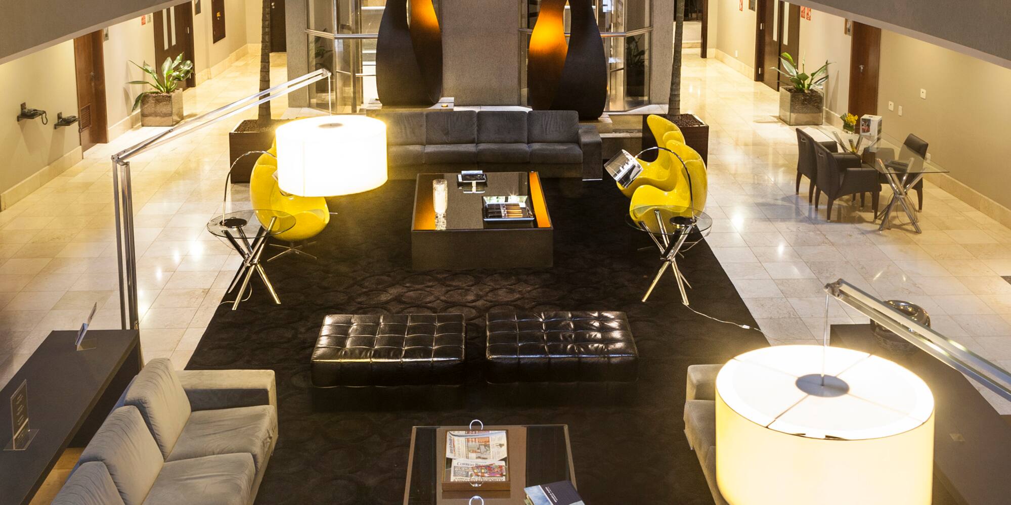 a room with a large black table and yellow chairs