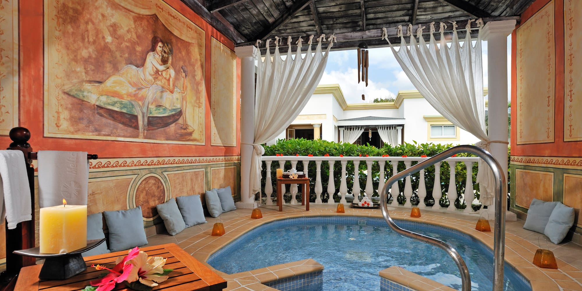 a hot tub with a table and chairs in a room with a painting on the wall