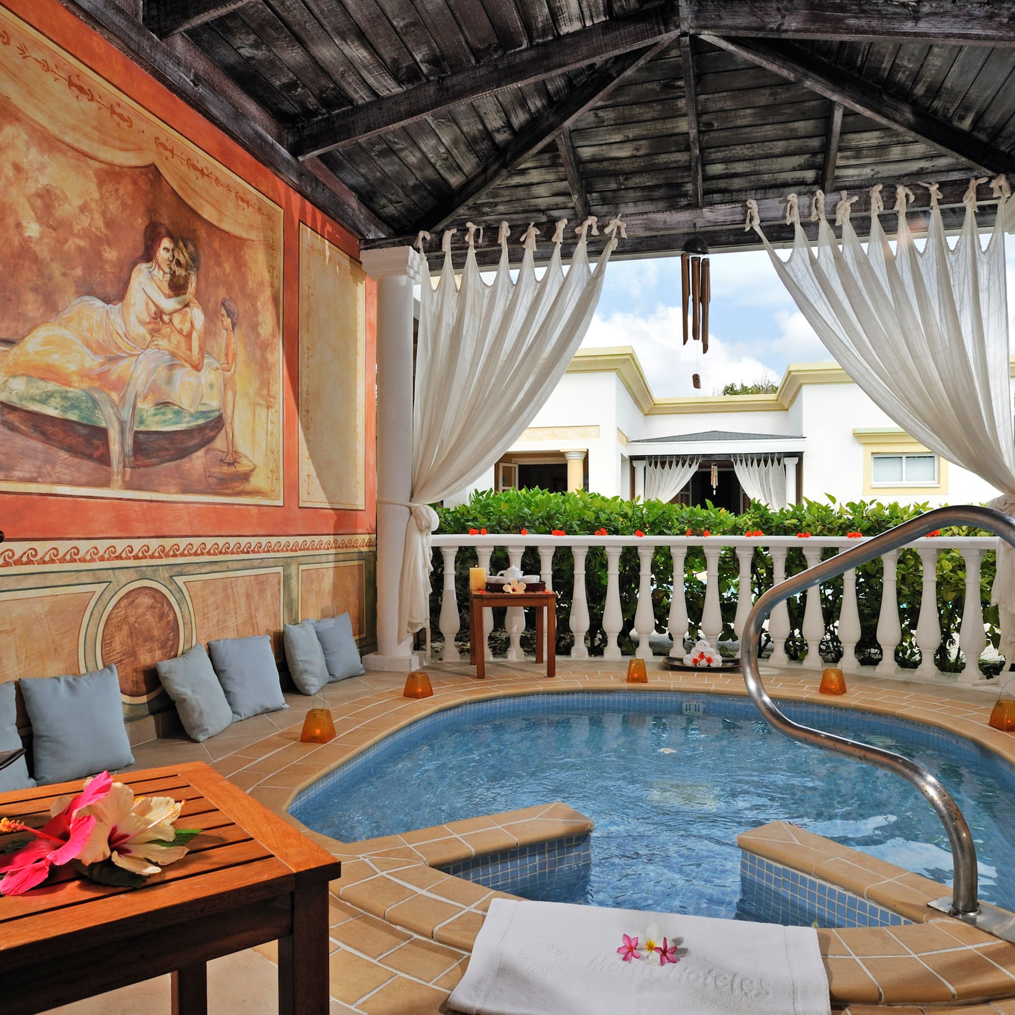 a hot tub with a table and chairs in a room with a painting on the wall