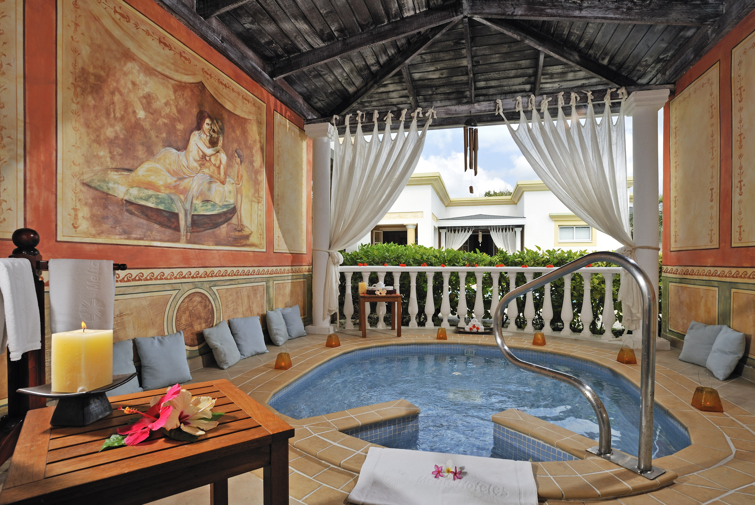 a hot tub with a table and chairs in a room with a painting on the wall