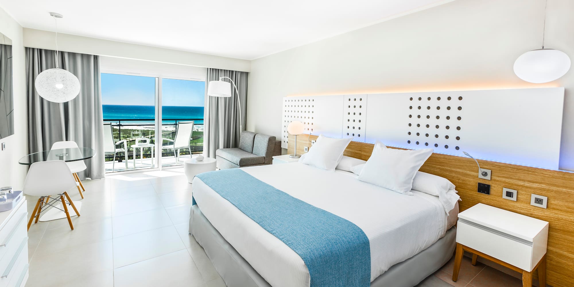 a bedroom with a large bed and a balcony overlooking the ocean