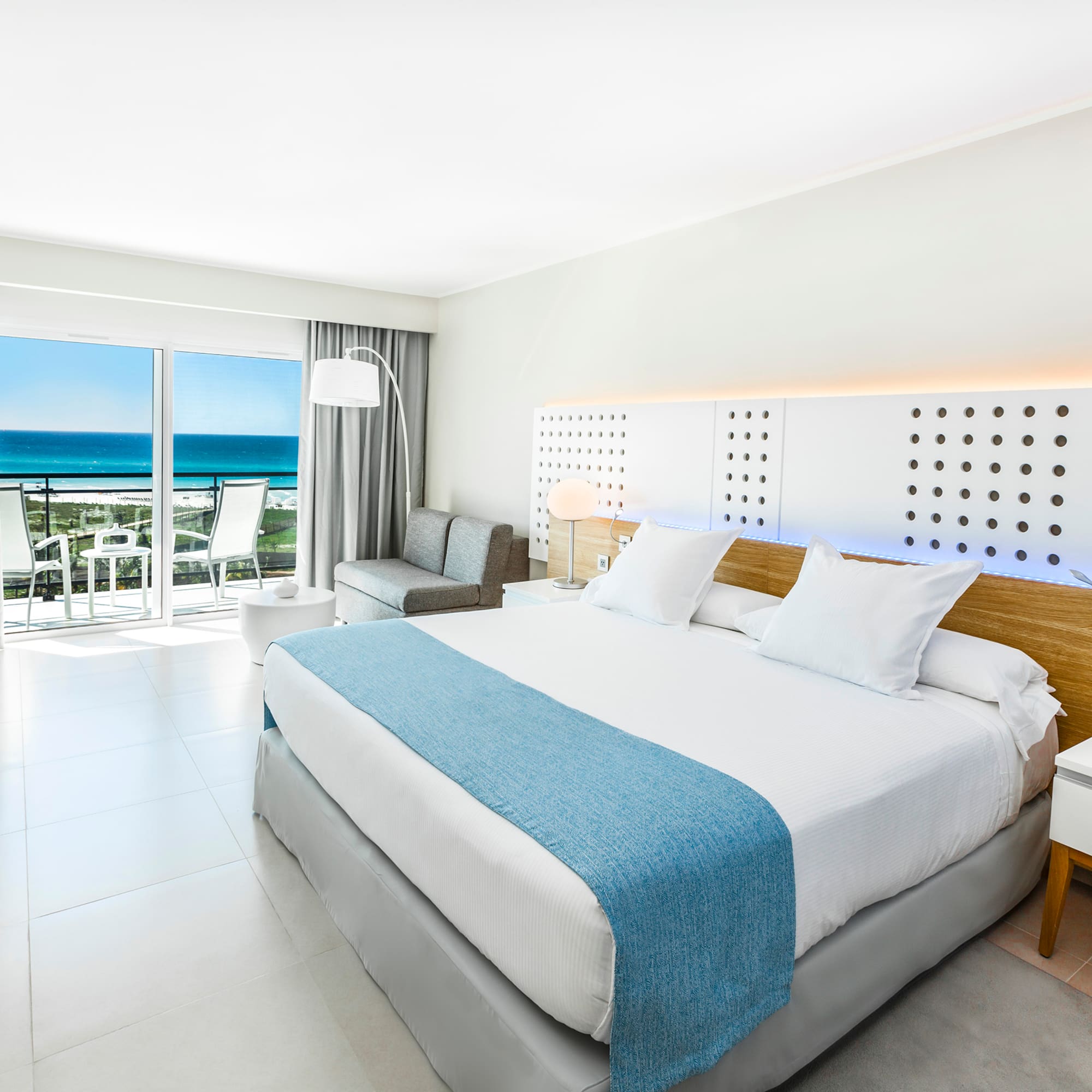 a bedroom with a large bed and a balcony overlooking the ocean