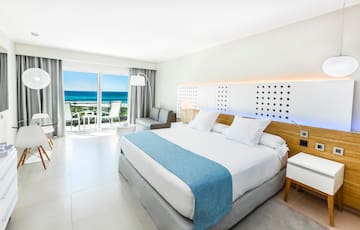 a bedroom with a large bed and a balcony overlooking the ocean
