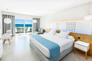 a bedroom with a large bed and a balcony overlooking the ocean