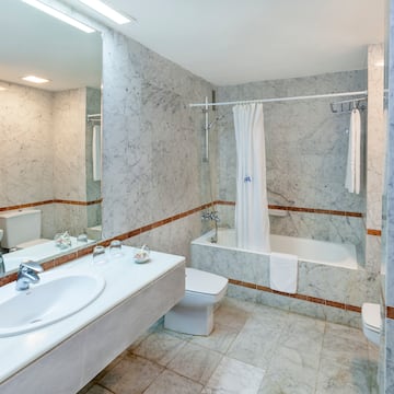 a bathroom with marble walls and a sink and toilet