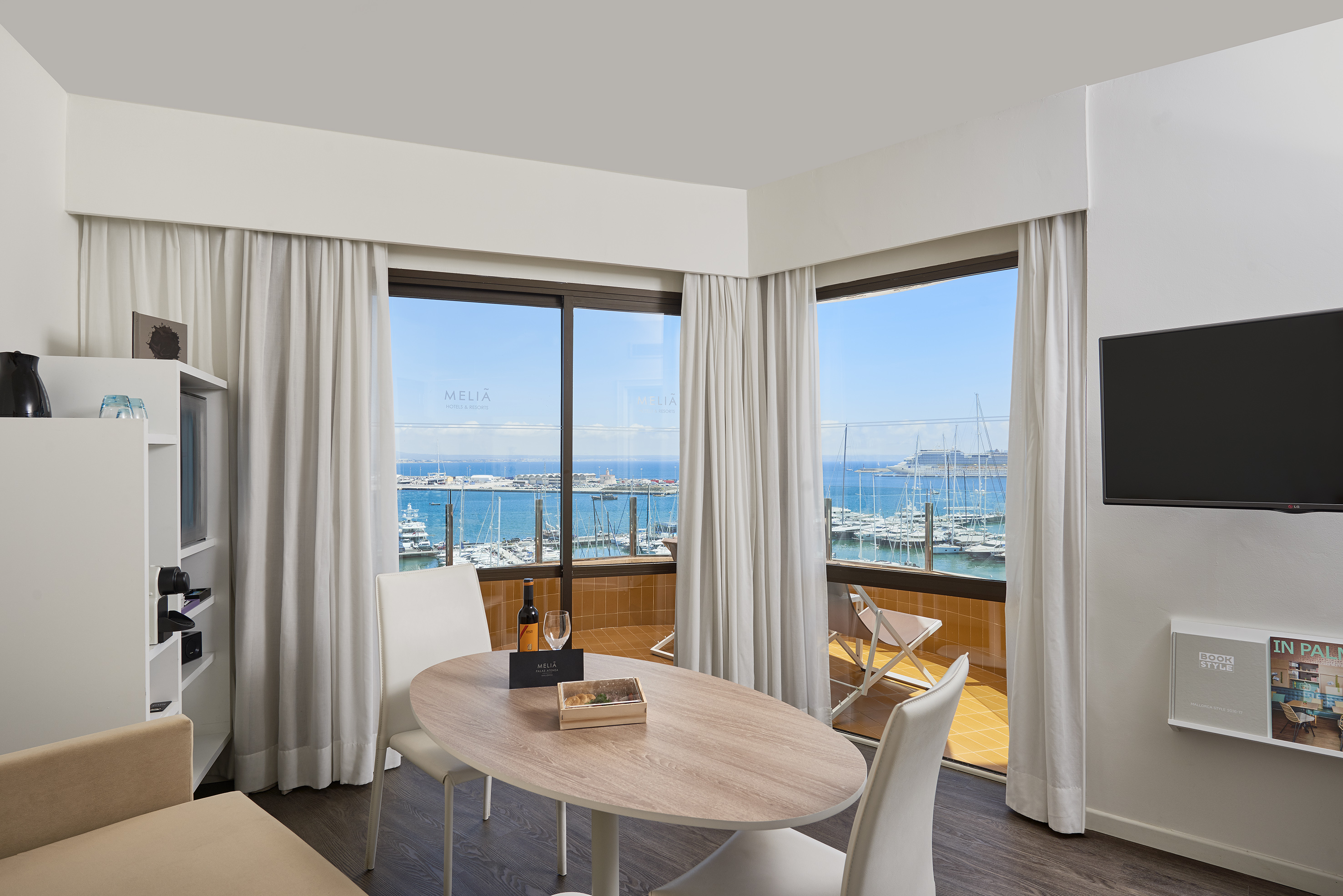 Meliá hotel suite with dining table, wine, and marina view balcony.