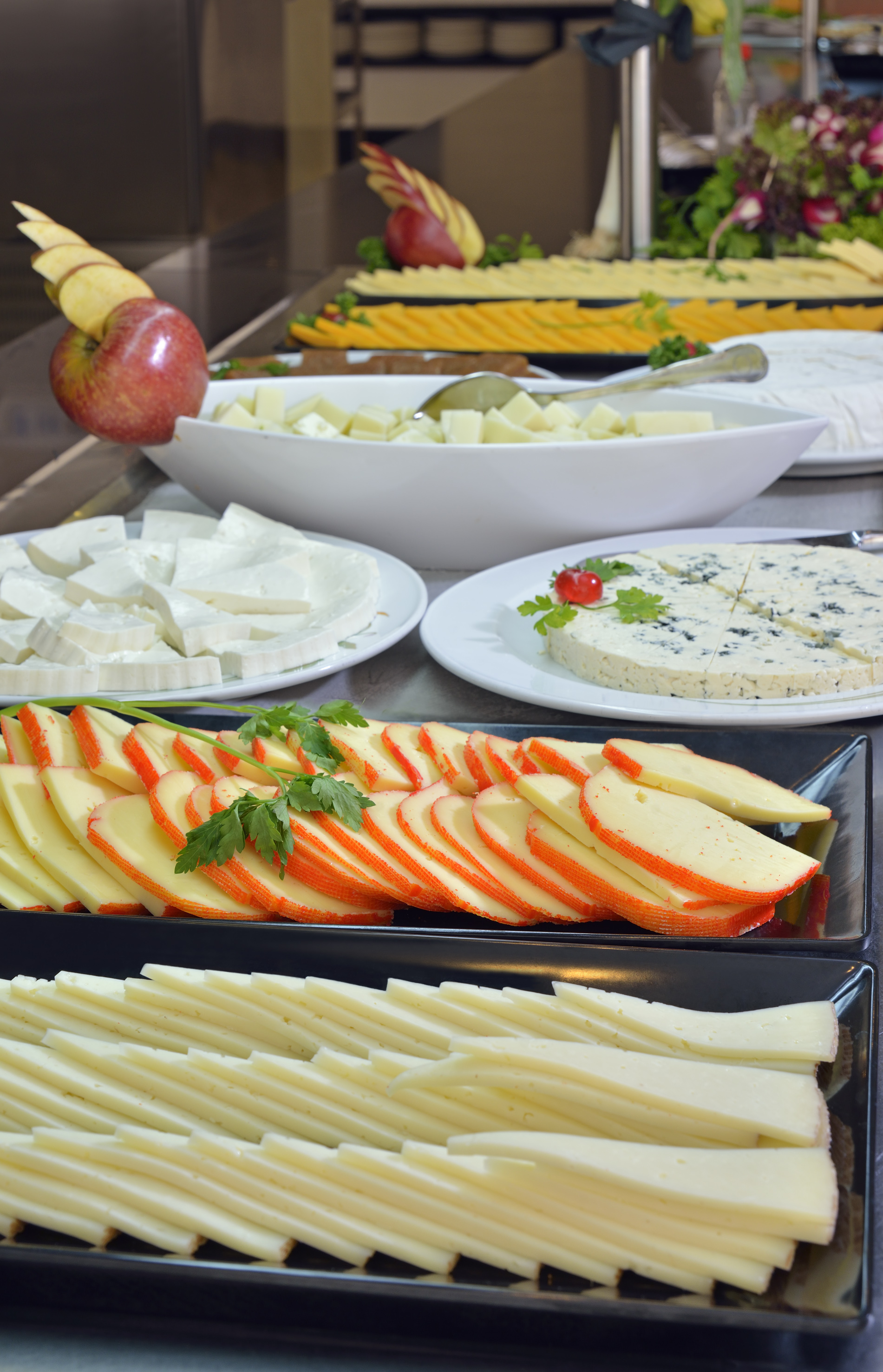 Assorted cheese buffet with sliced, cubed, and blue cheese, garnished with apples.