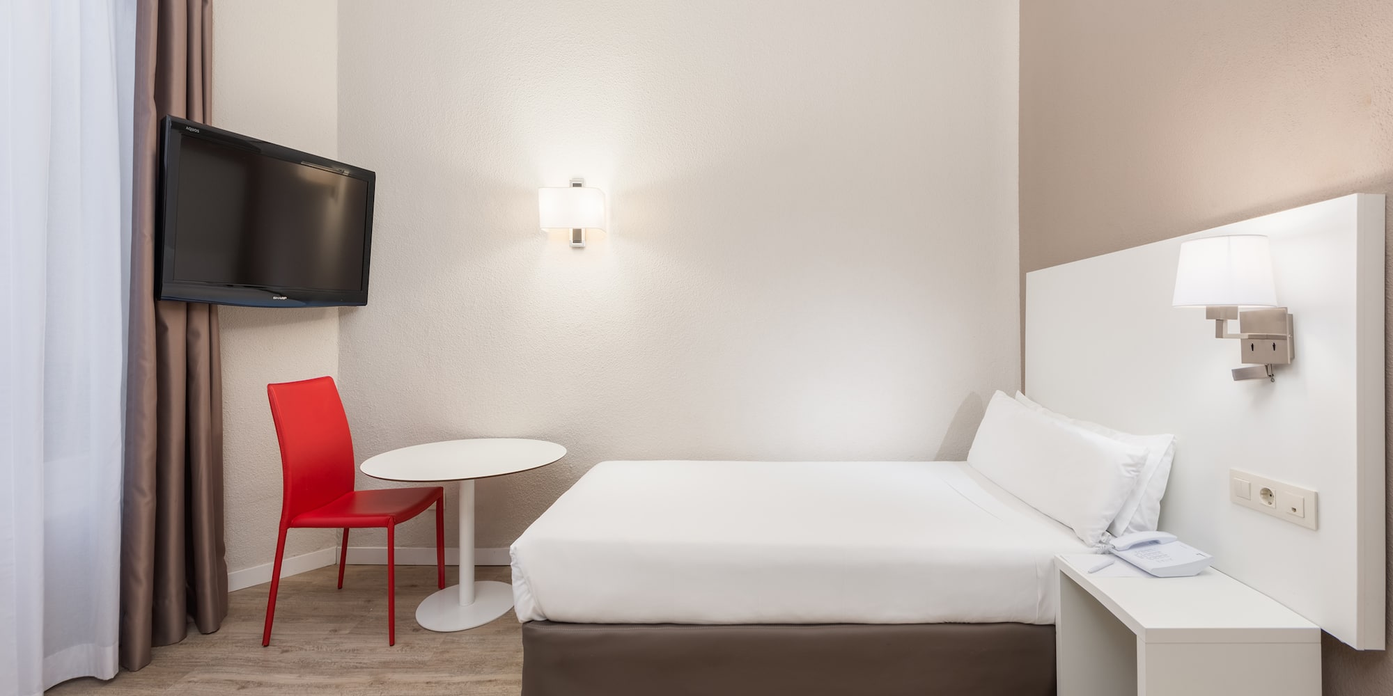 a room with a bed and a table and a tv