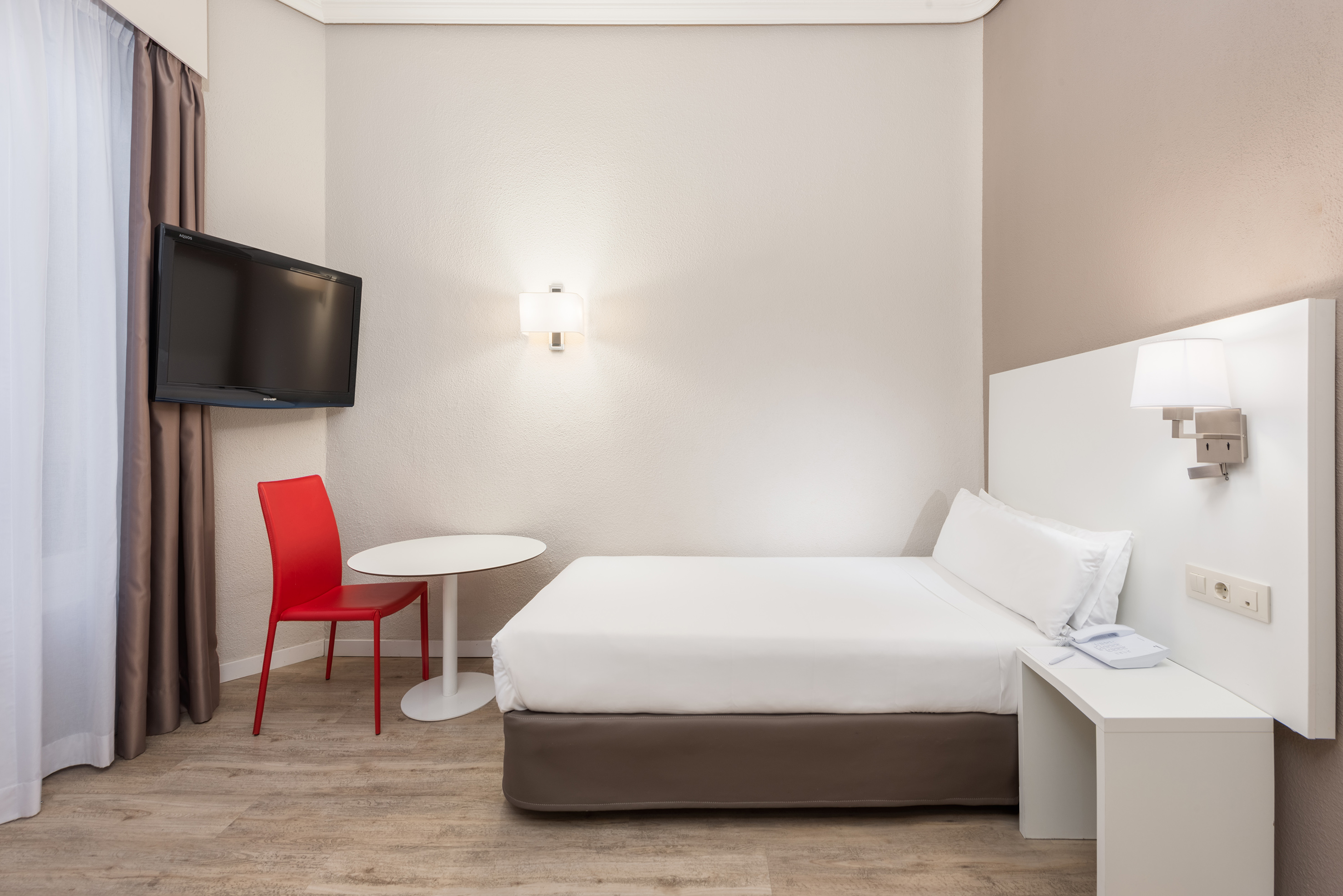 a room with a bed and a table and a tv