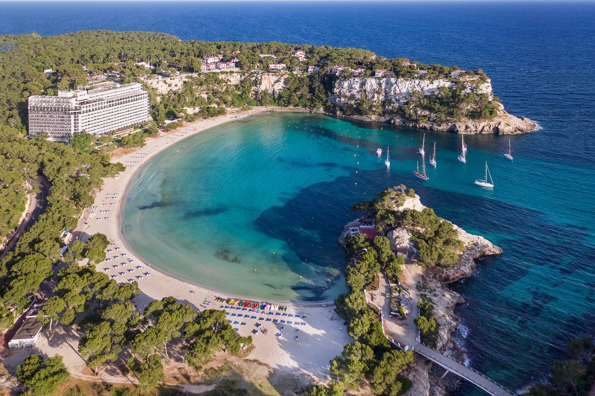 Aerial of Cala Galdana, Majorca: Melia hotel, sandy beach, turquoise bay, sailboats.
