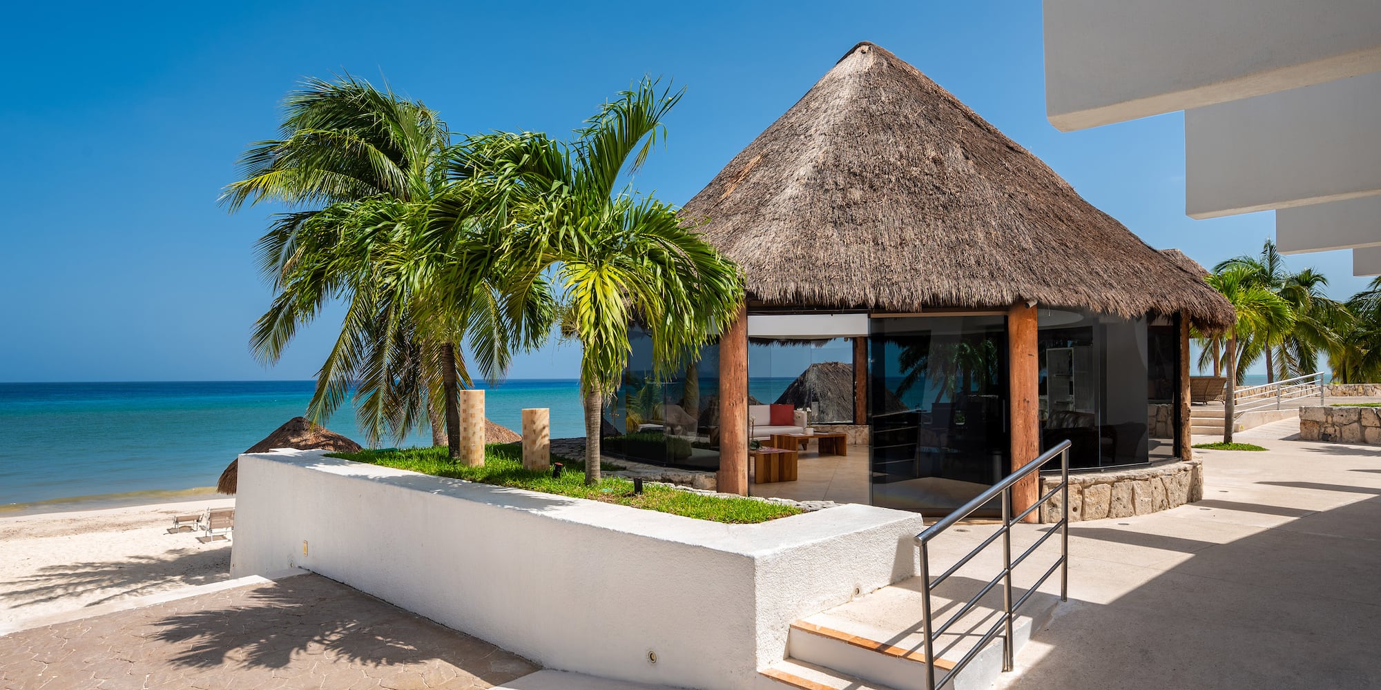 a building with a thatched roof and palm trees