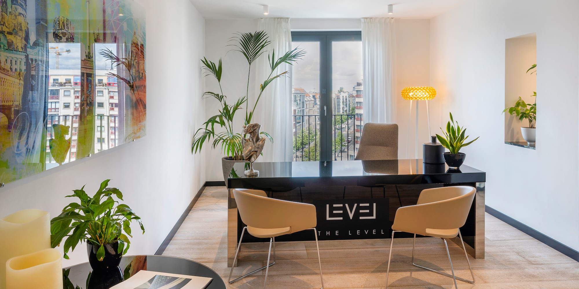Bright modern office with black 'LEVEL' desk, green plants, and city window view.