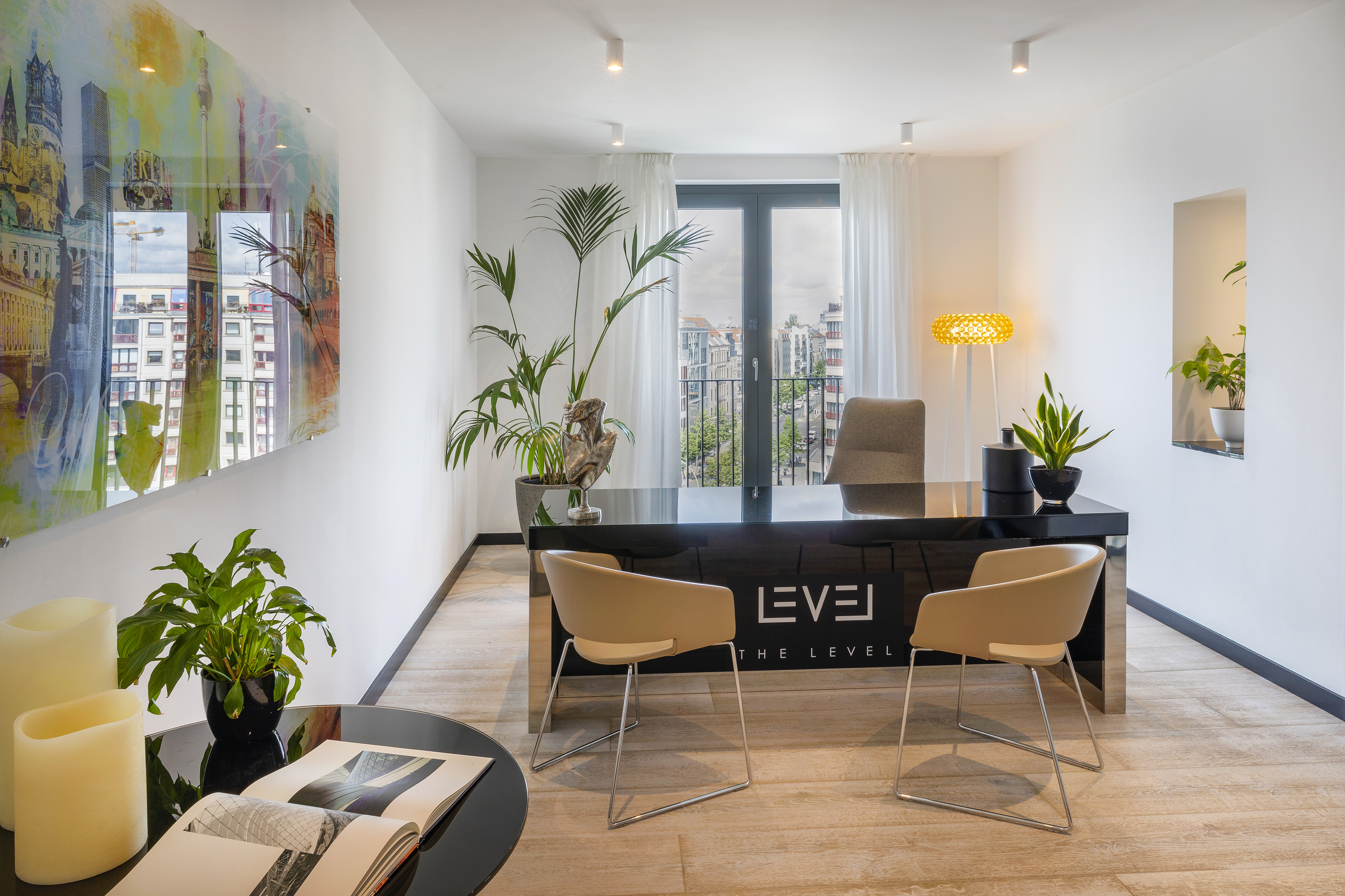 Modern office with sleek black desk, beige chairs, plants, and city view.