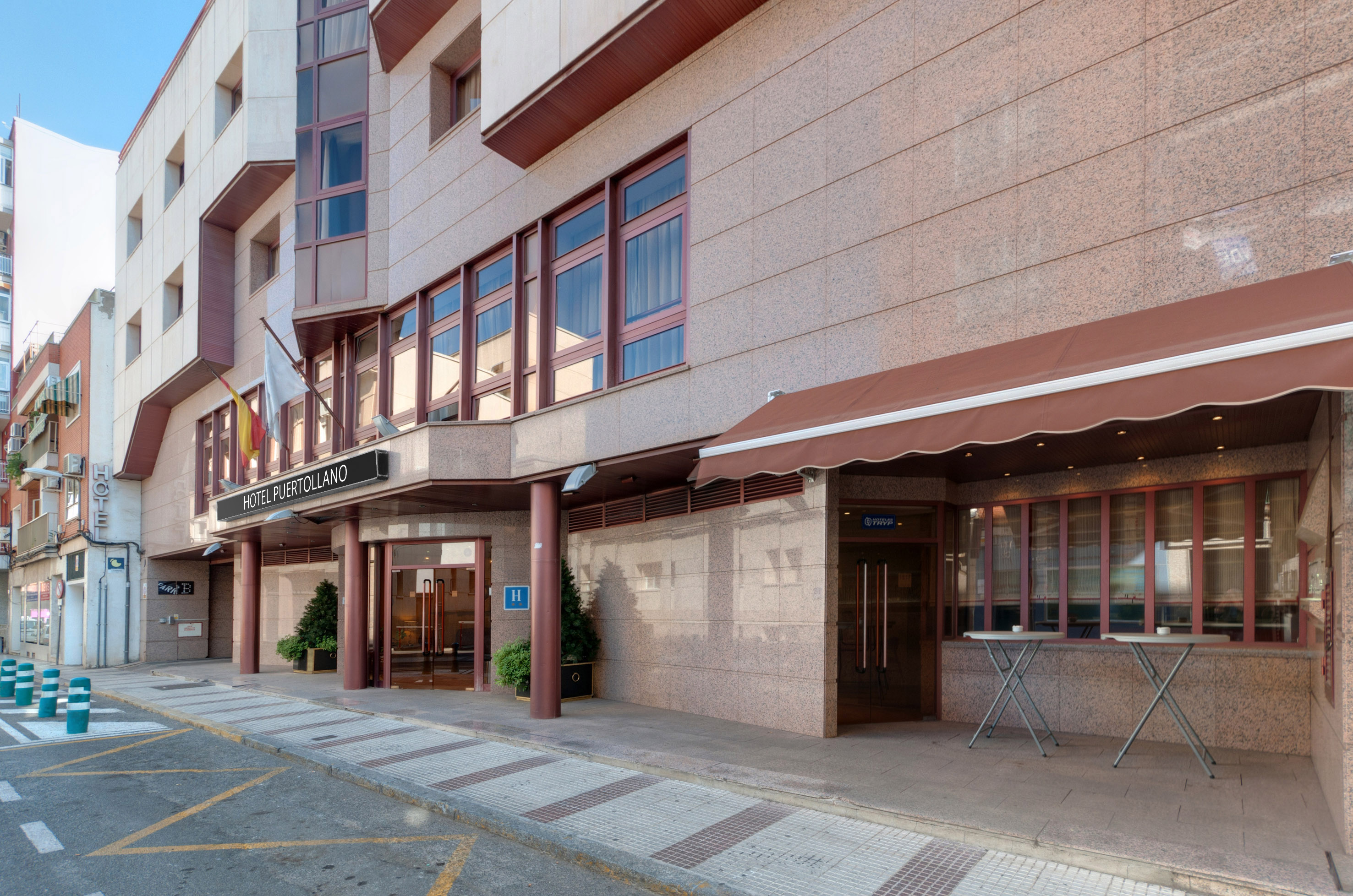 Hotel Puertollano main entrance, modern granite facade with brown awnings.