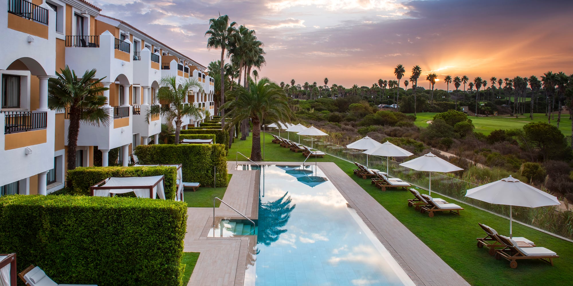 a pool with lounge chairs and trees in the background