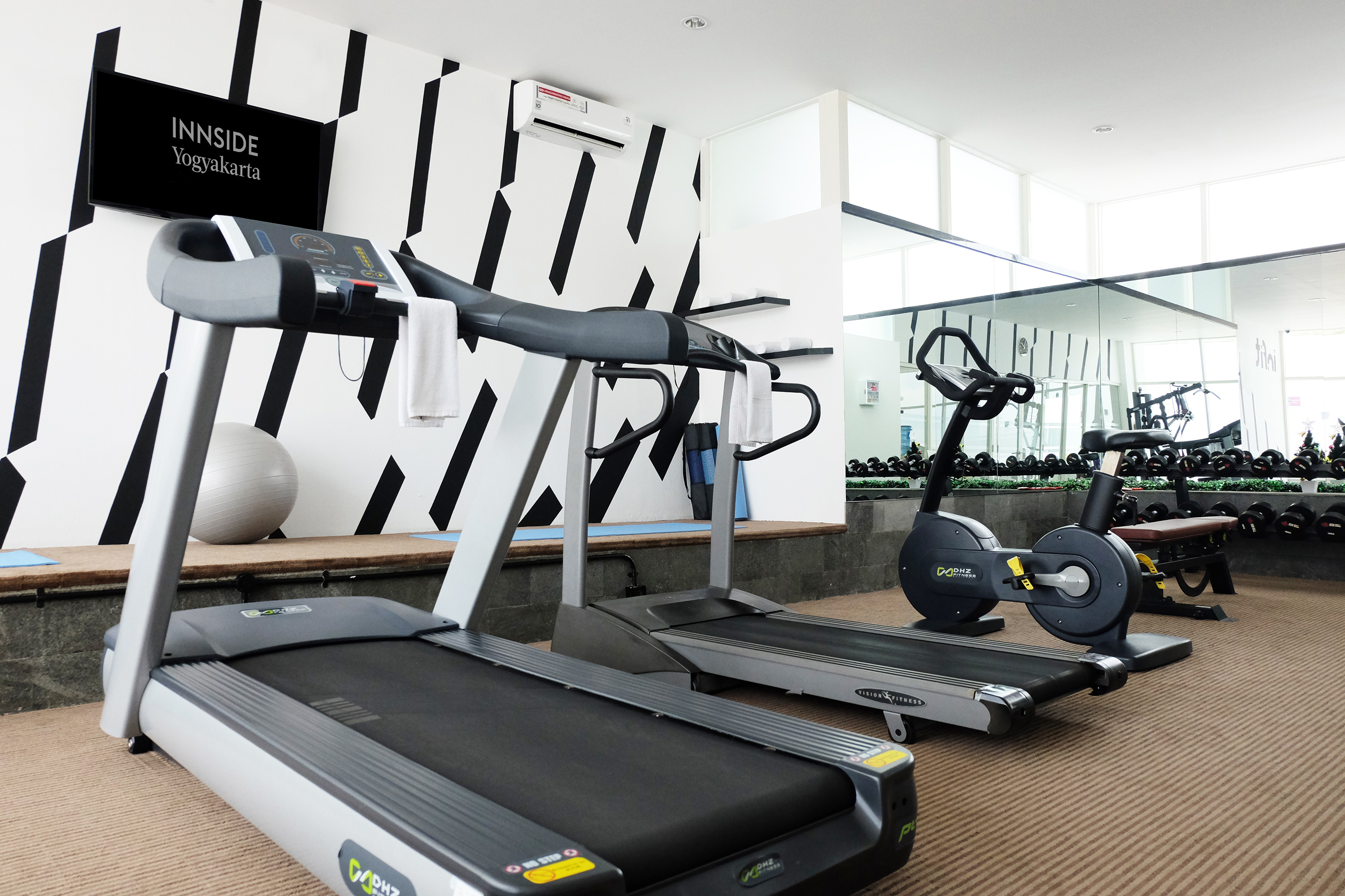 INNSIDE Yogyakarta gym with treadmills, exercise bike, and weight rack.