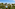 Sunny resort with swimming pool, white hotel buildings, and lush palm trees.