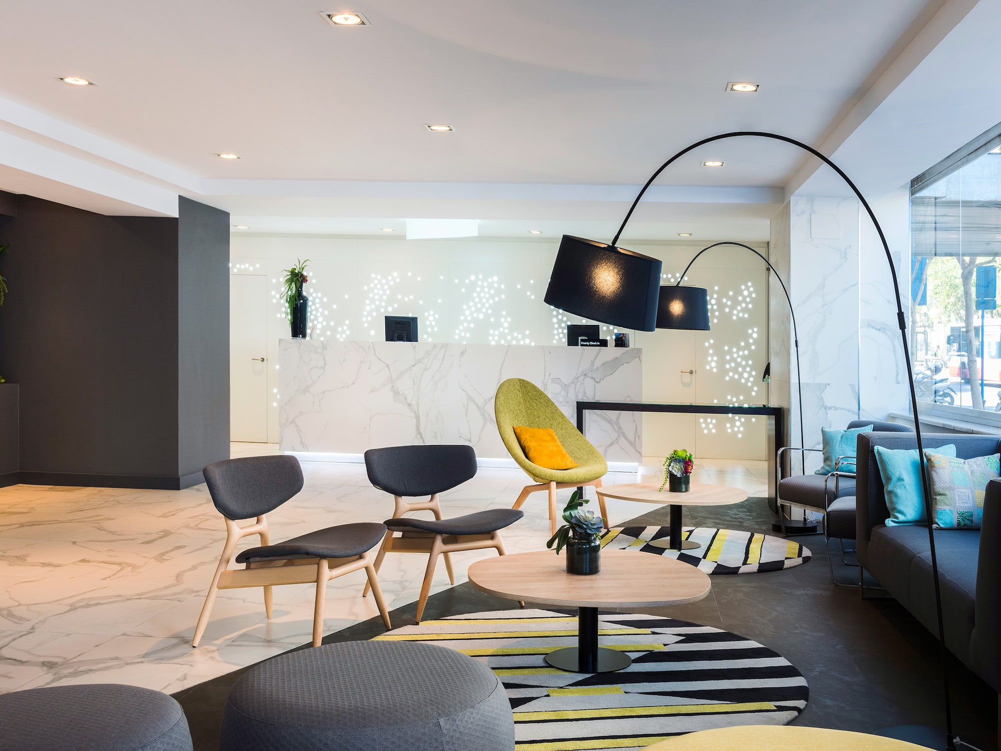 Lobby de hotel moderno con recepción de mármol y área de descanso.