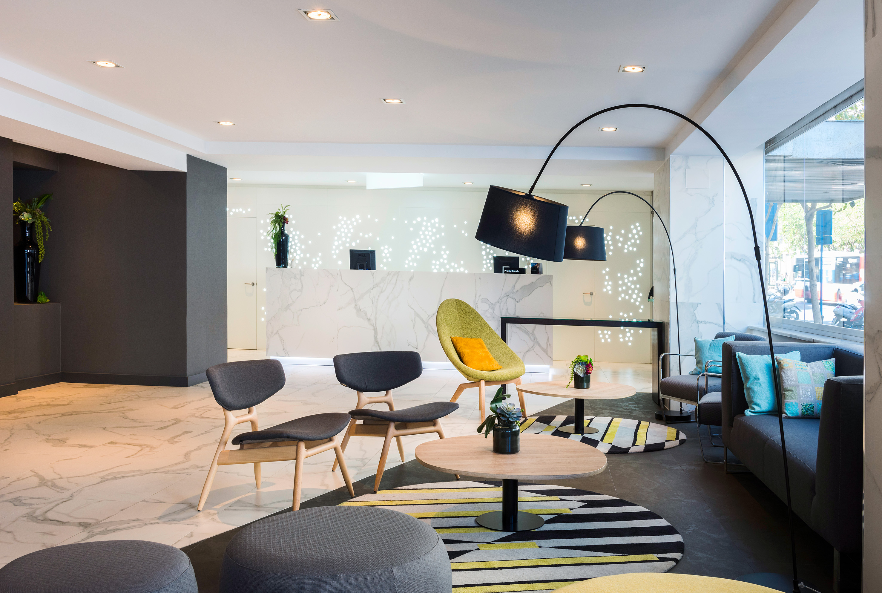 Lobby de hotel moderno con recepción de mármol y área de descanso.