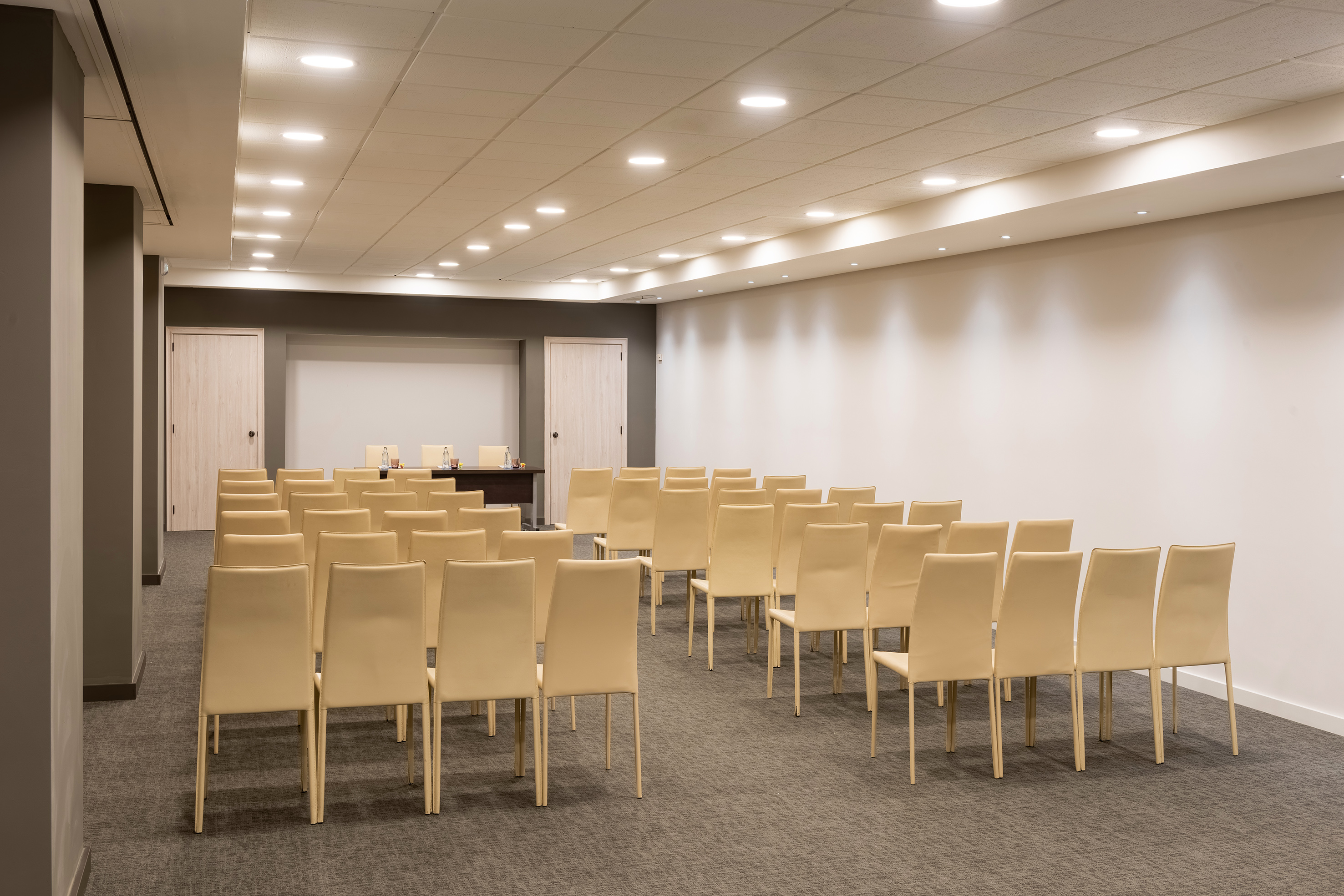 Empty modern conference room with beige chairs and recessed lighting.