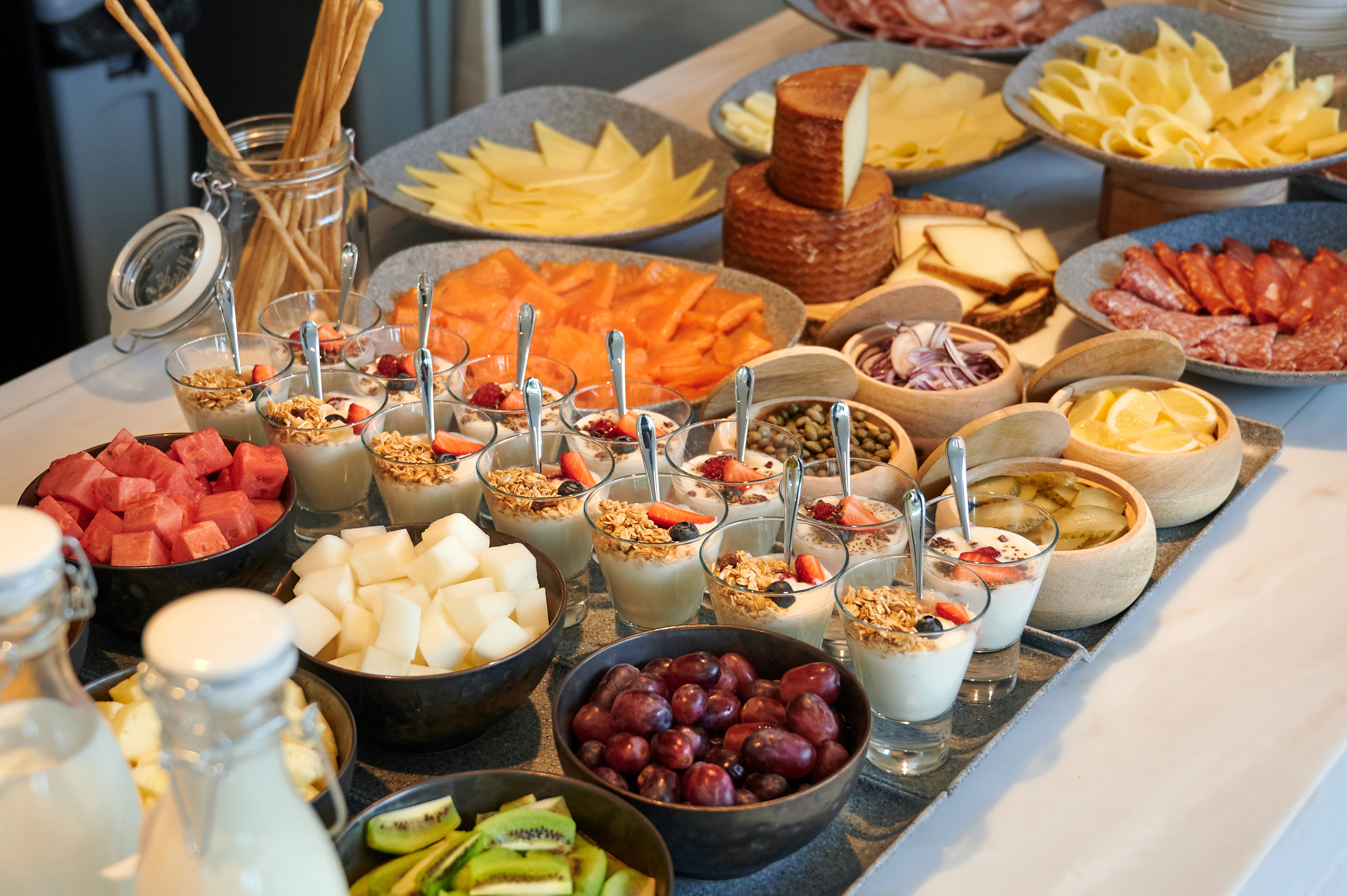 Hotel breakfast buffet: yogurt parfaits, fresh fruit, cheese, salmon, deli meats.