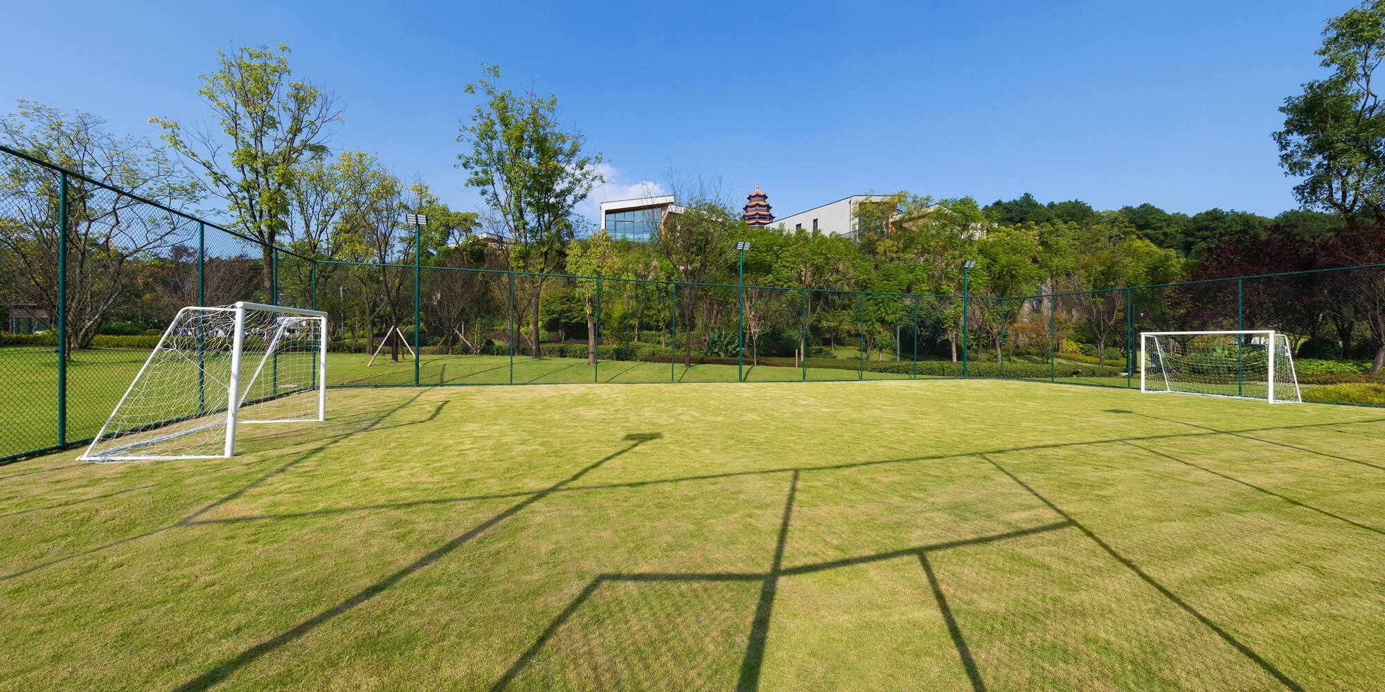a football field with a fence and trees in the background