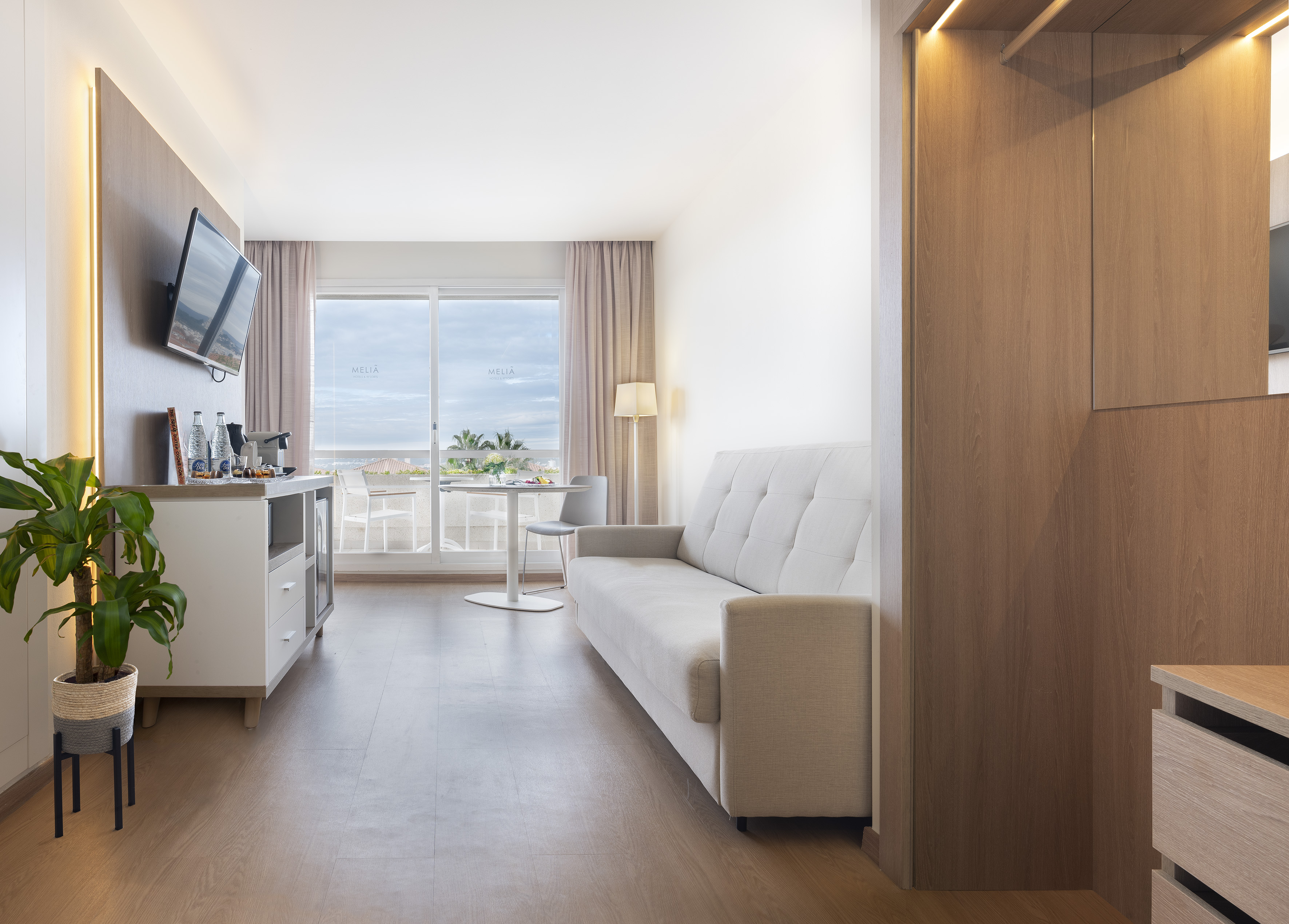Meliá hotel suite living room with sofa, TV, and balcony sea view.