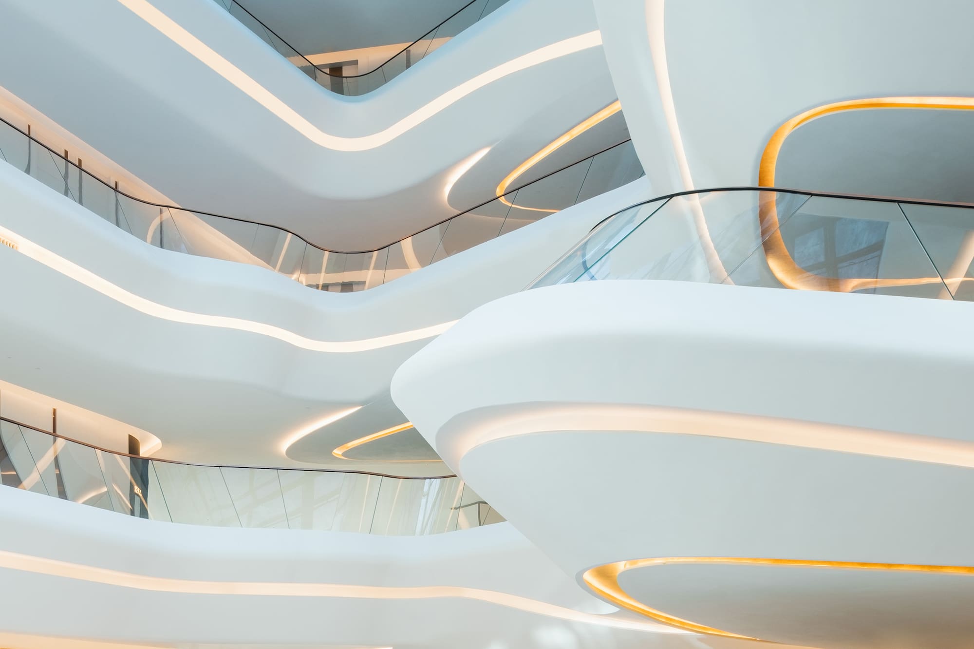 Curved white atrium interior with multi-level balconies and warm accent lighting.