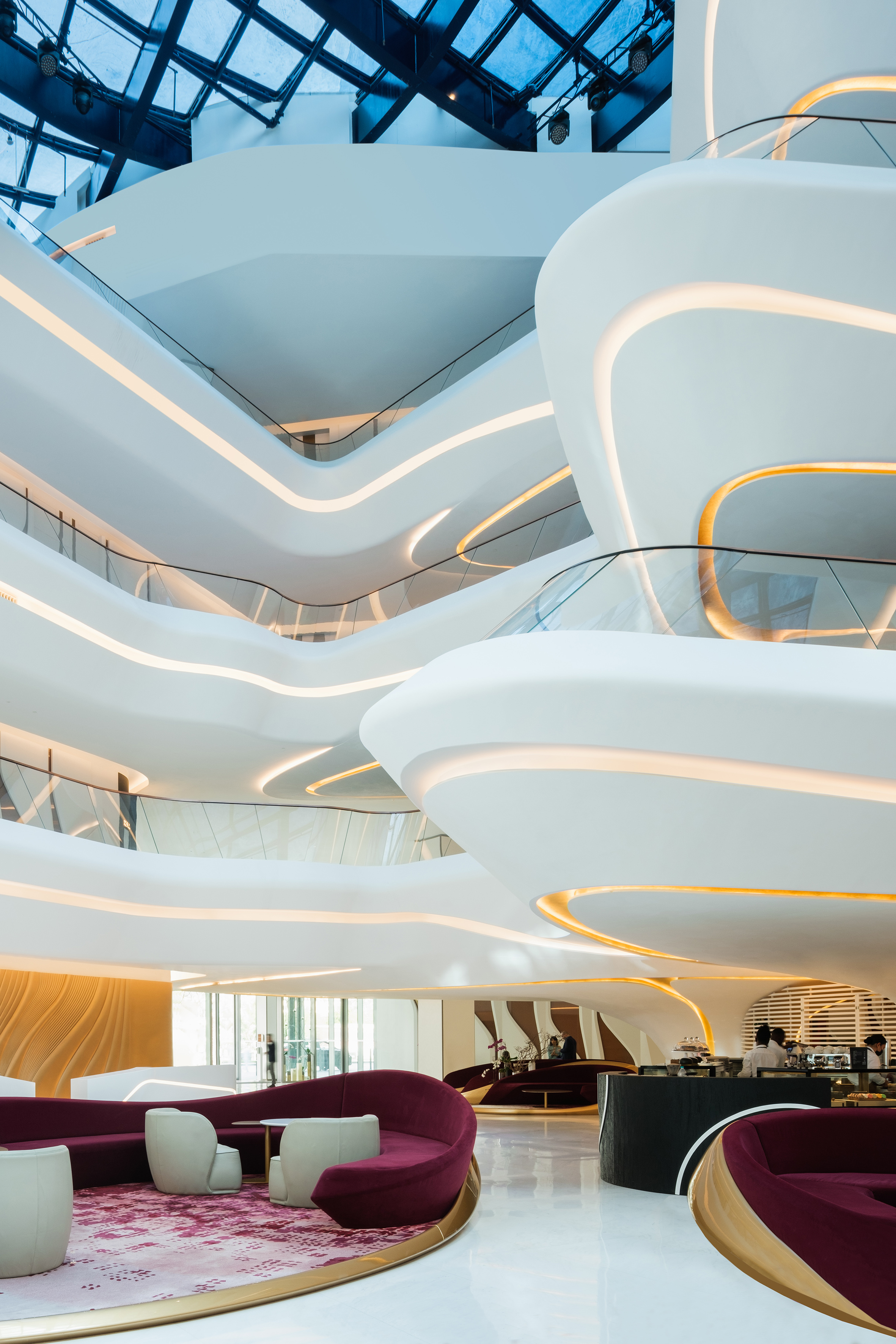 Curved white atrium interior with multi-level balconies and warm accent lighting.