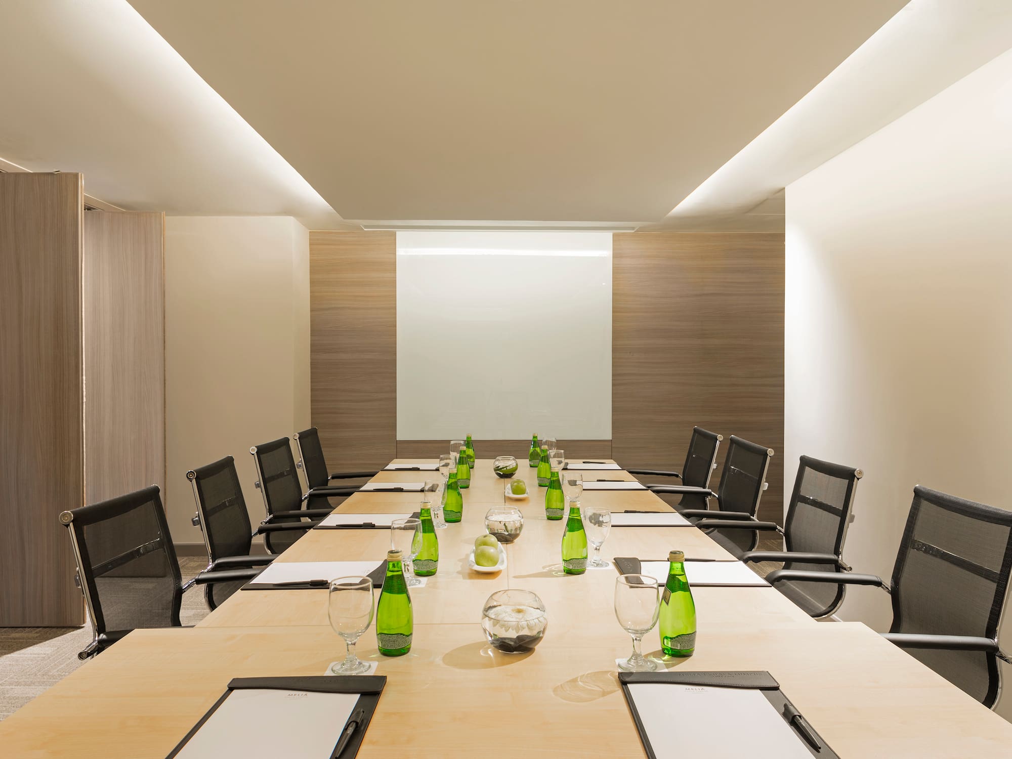 a conference room with a table with green bottles and chairs