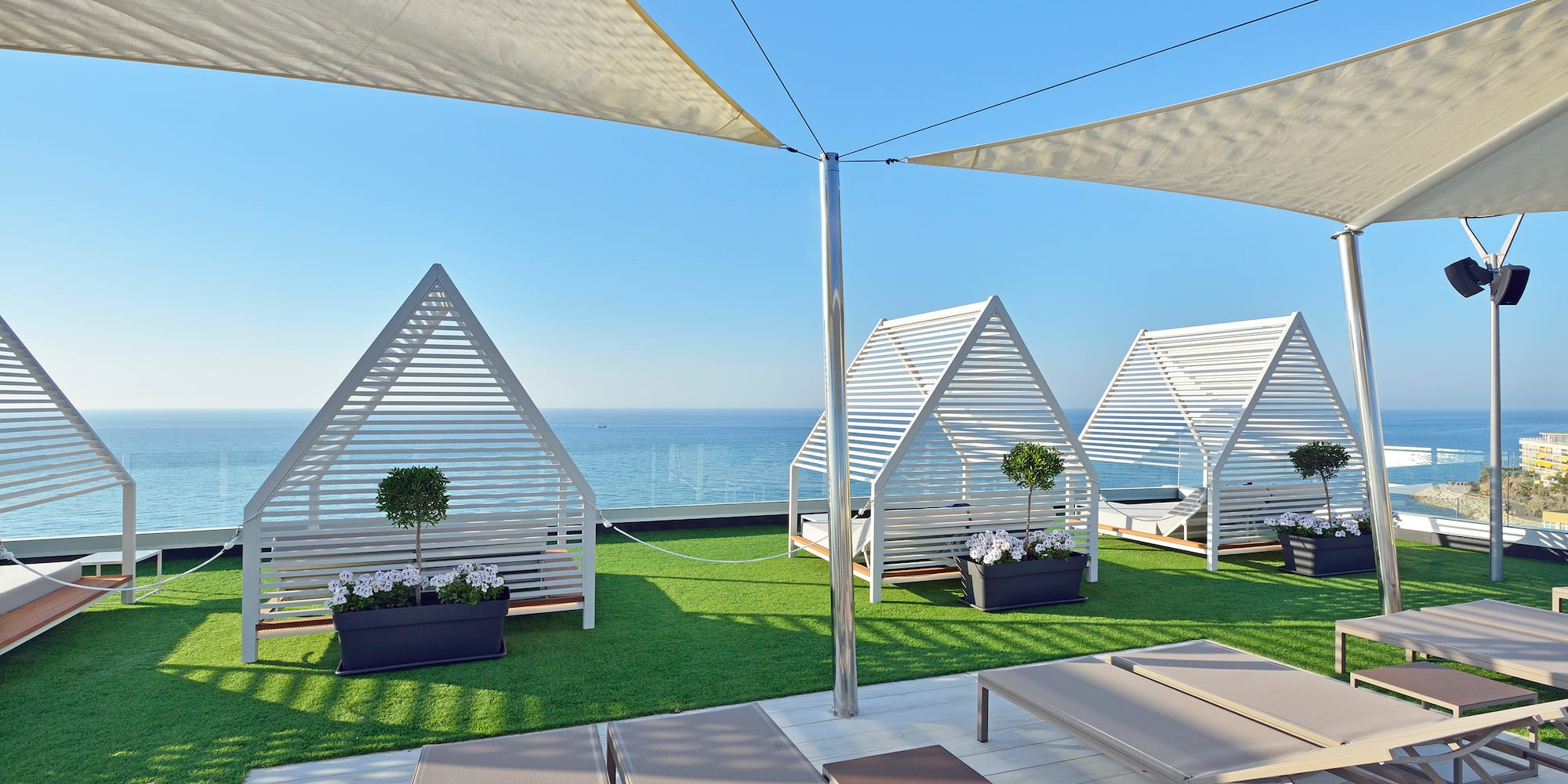 a deck with white tents and chairs on grass with a body of water