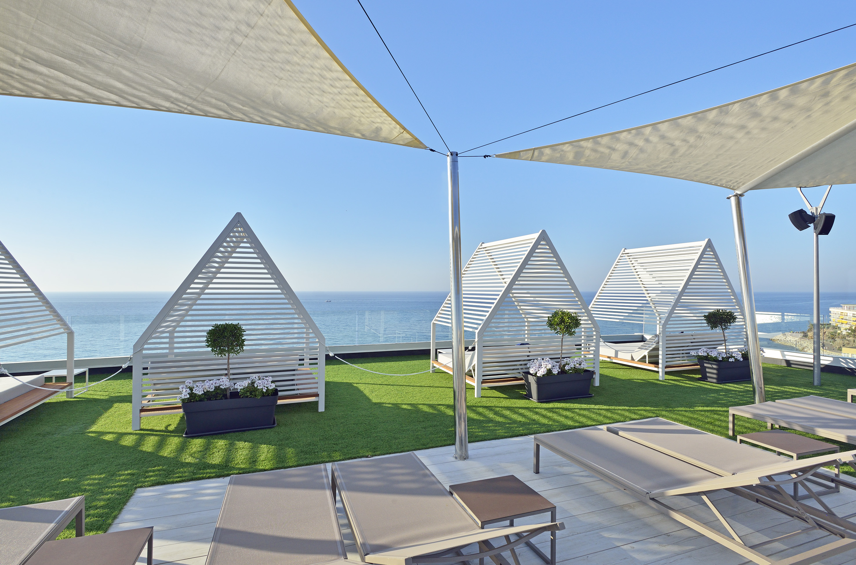 Rooftop ocean view terrace with modern white cabanas and lounge chairs.
