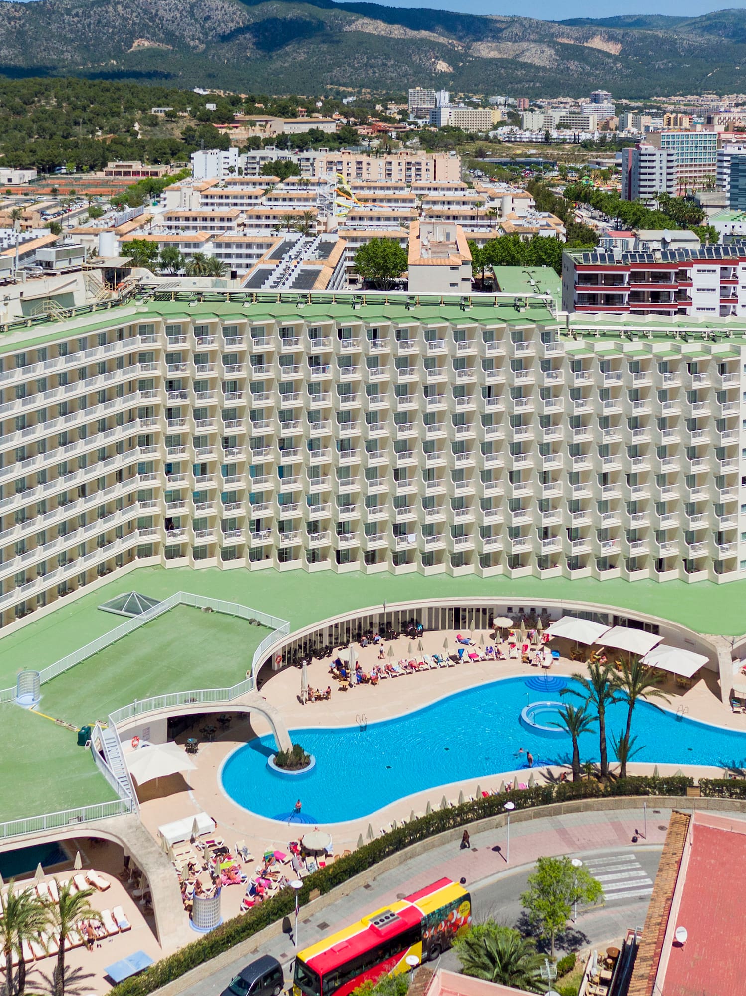 a large building with a pool and a city in the background