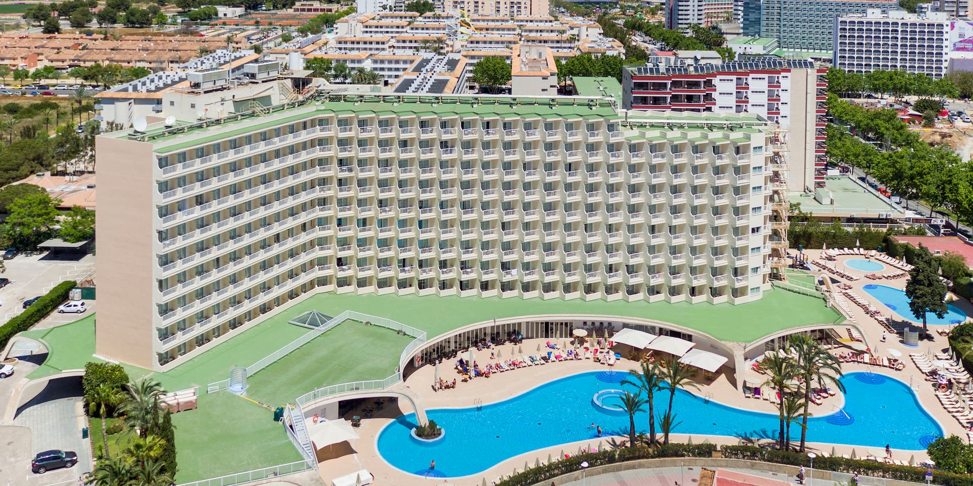 a large building with a pool and a city in the background