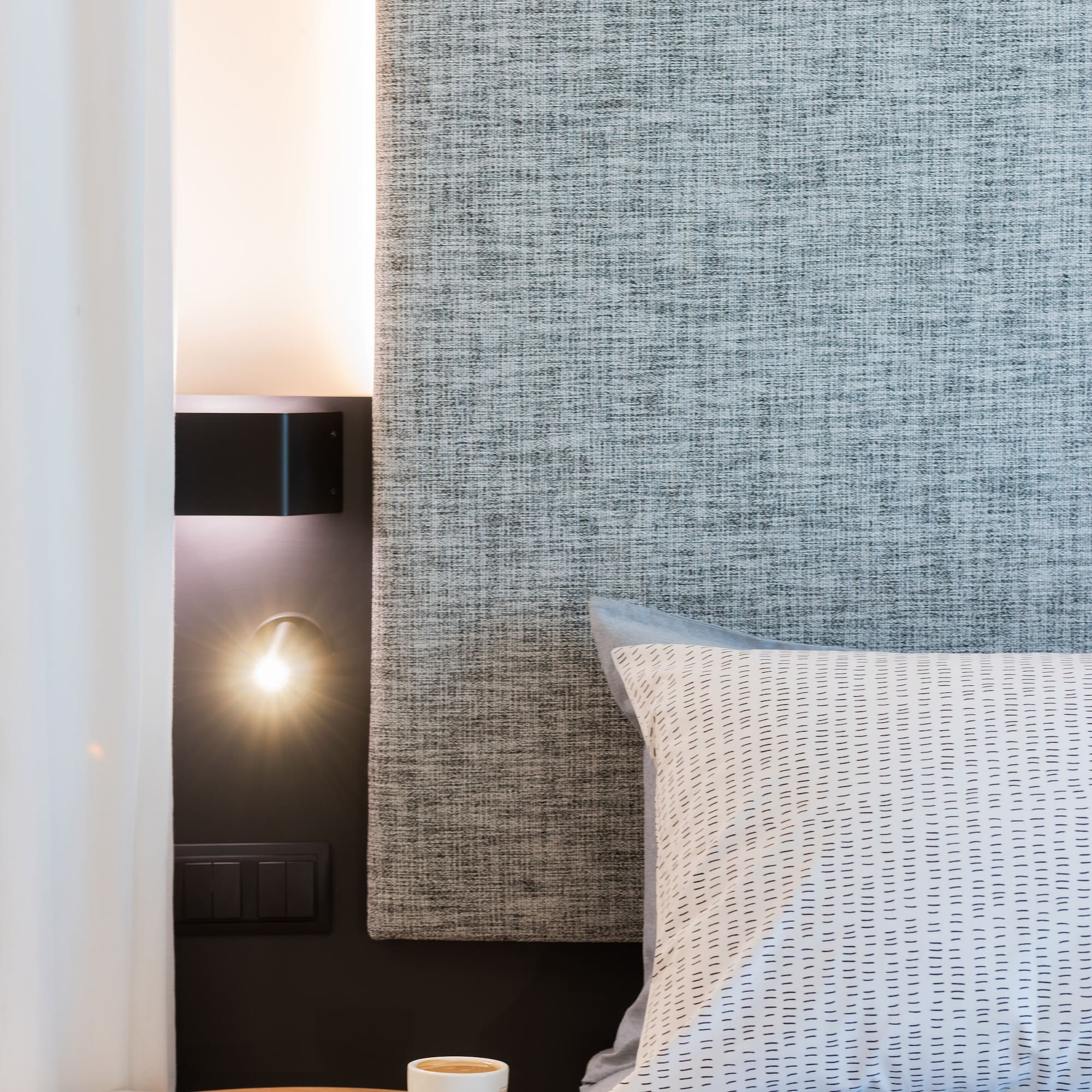 a coffee cup on a table next to a bed