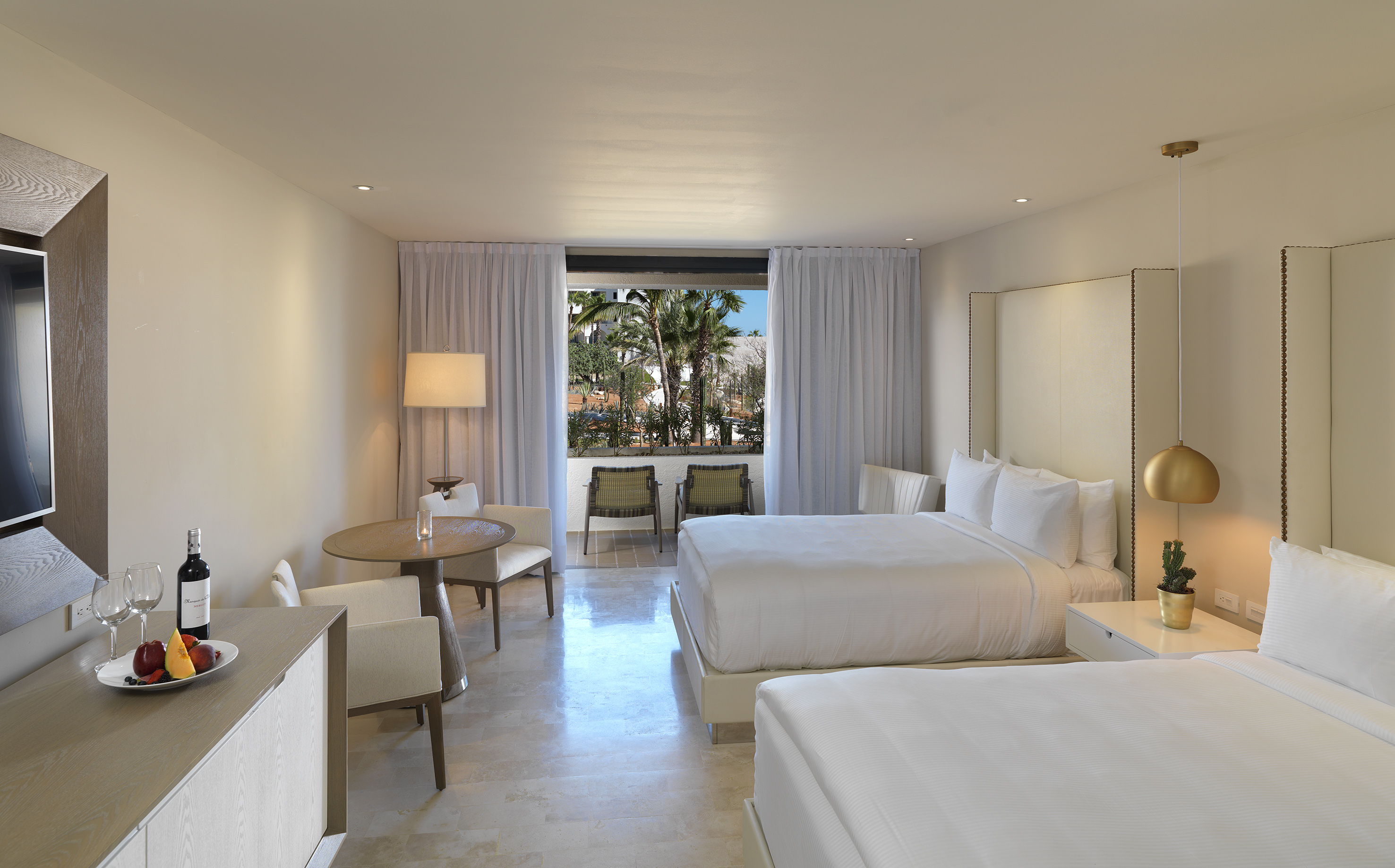 Modern hotel room with two beds, private balcony, and lush tropical view.