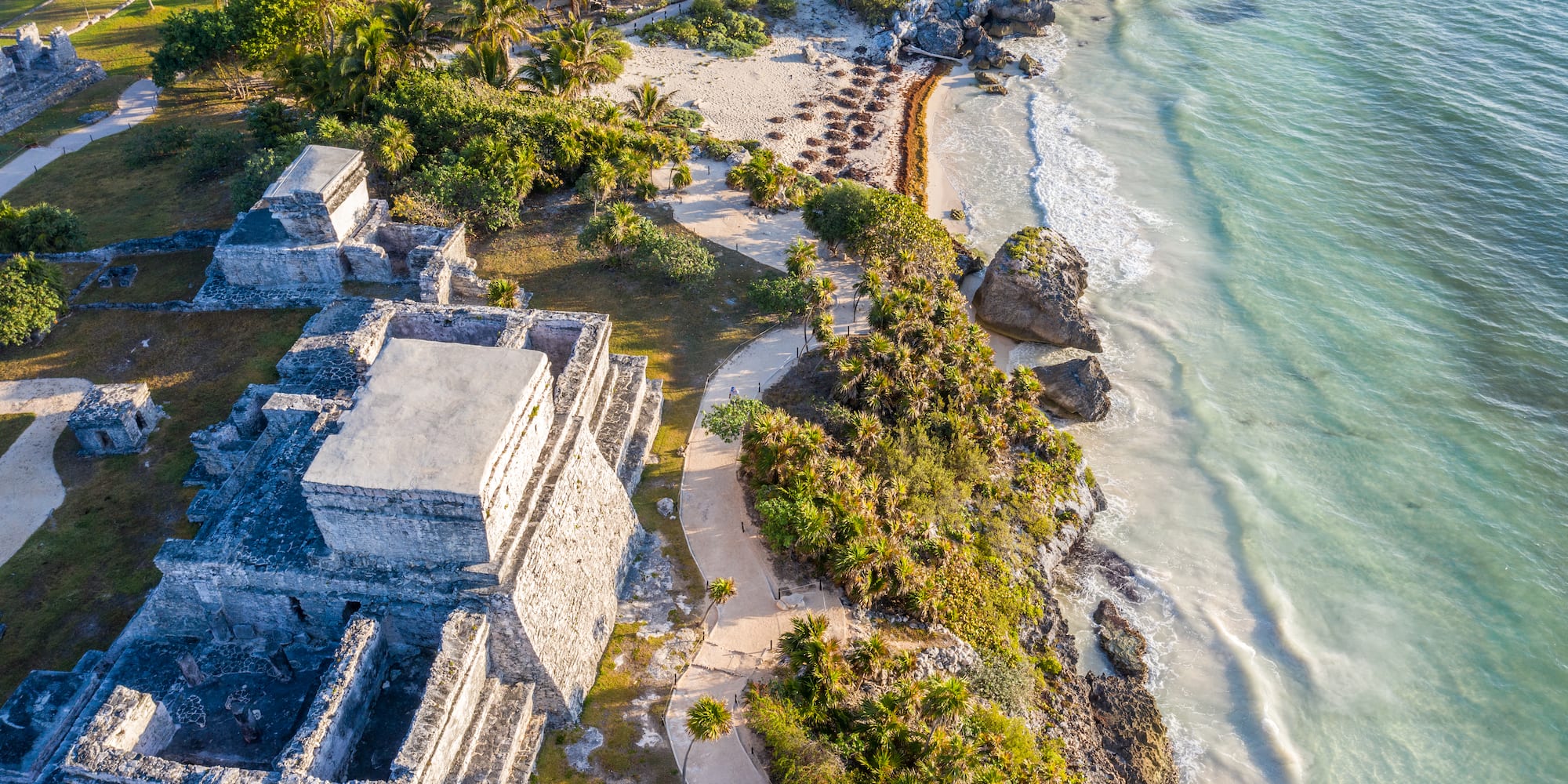 an aerial view of a beach with a building and palm trees