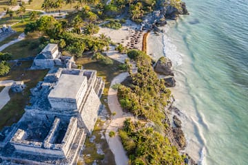 an aerial view of a beach with a building and palm trees