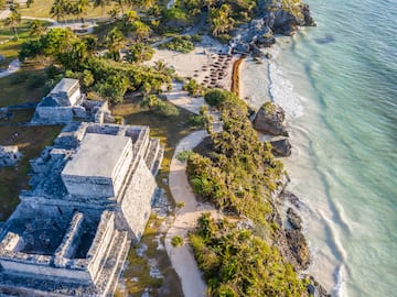 an aerial view of a beach with a building and palm trees