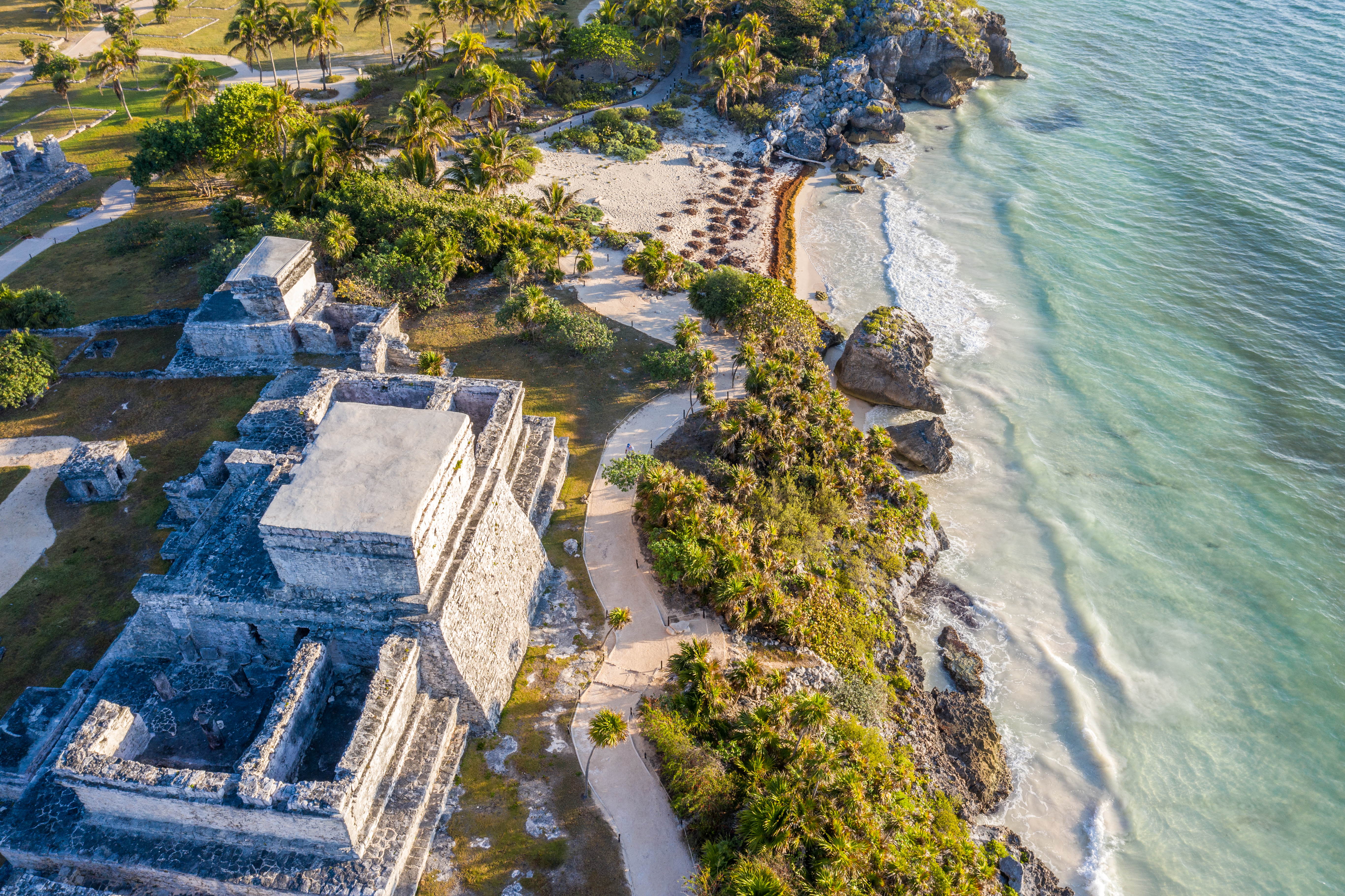 an aerial view of a beach with a building and palm trees