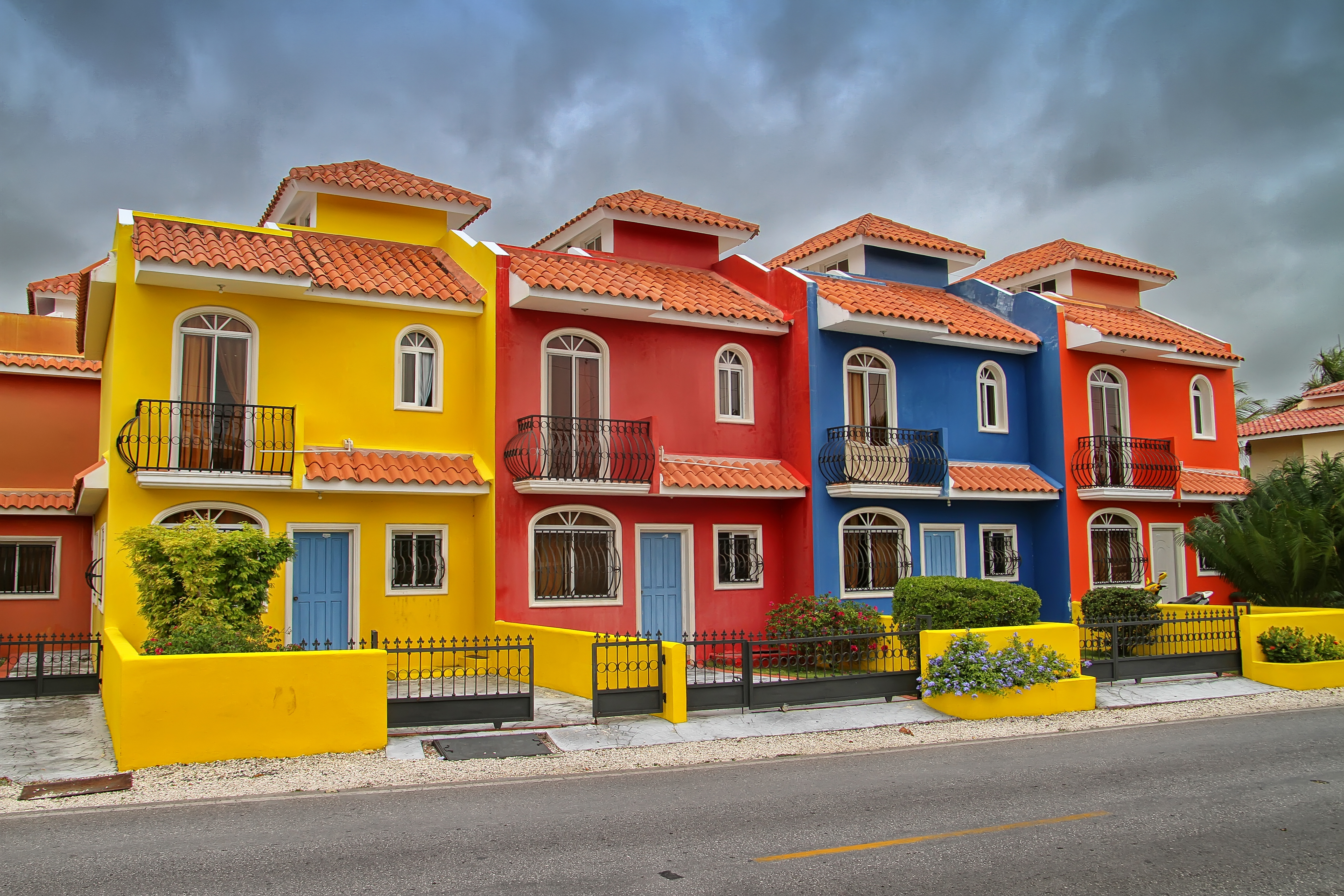 Colorful yellow, red, blue, orange townhouses with tiled roofs and balconies.