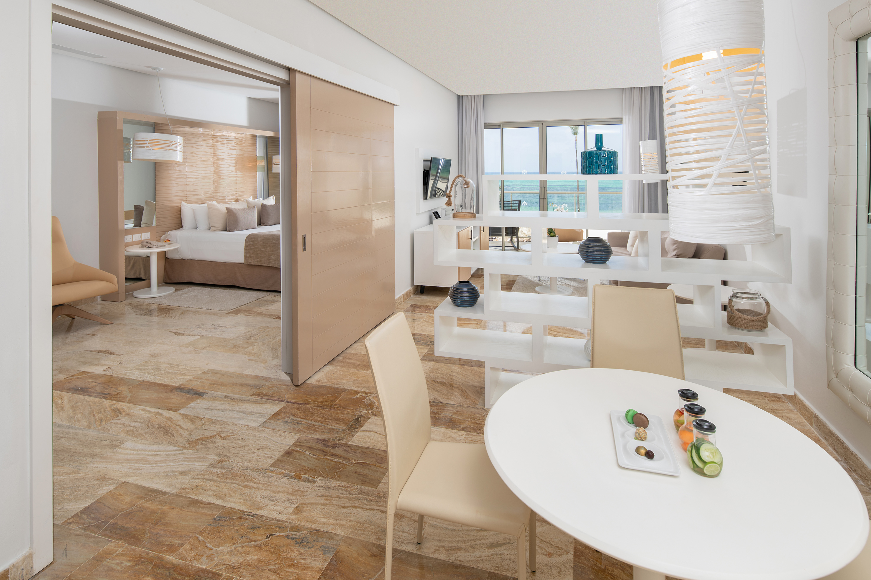 Luxury hotel suite with ocean view, modern living area, and separate bedroom.