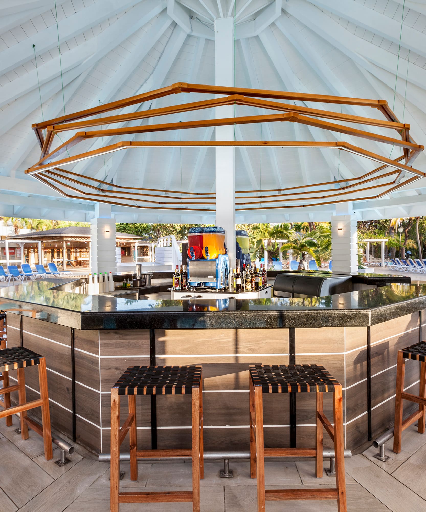 a bar with chairs and a pool in the background