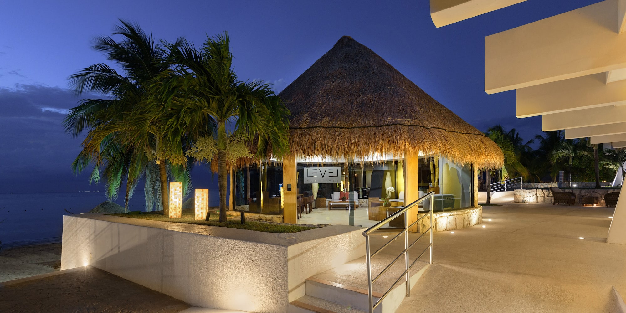 a building with a thatched roof and palm trees